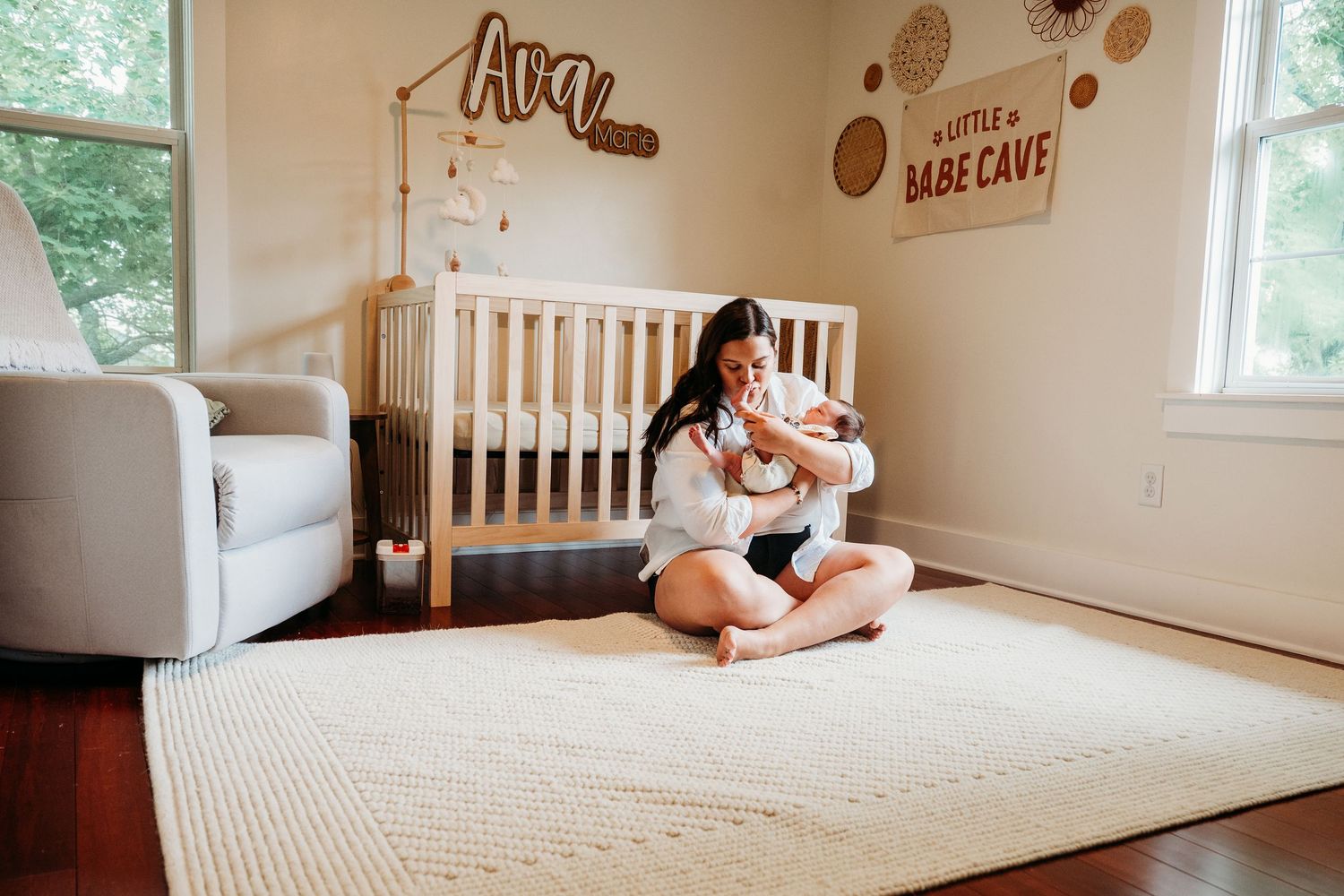 A mattress rests on the floor of a bright, minimalist room with natural light streaming through windows.