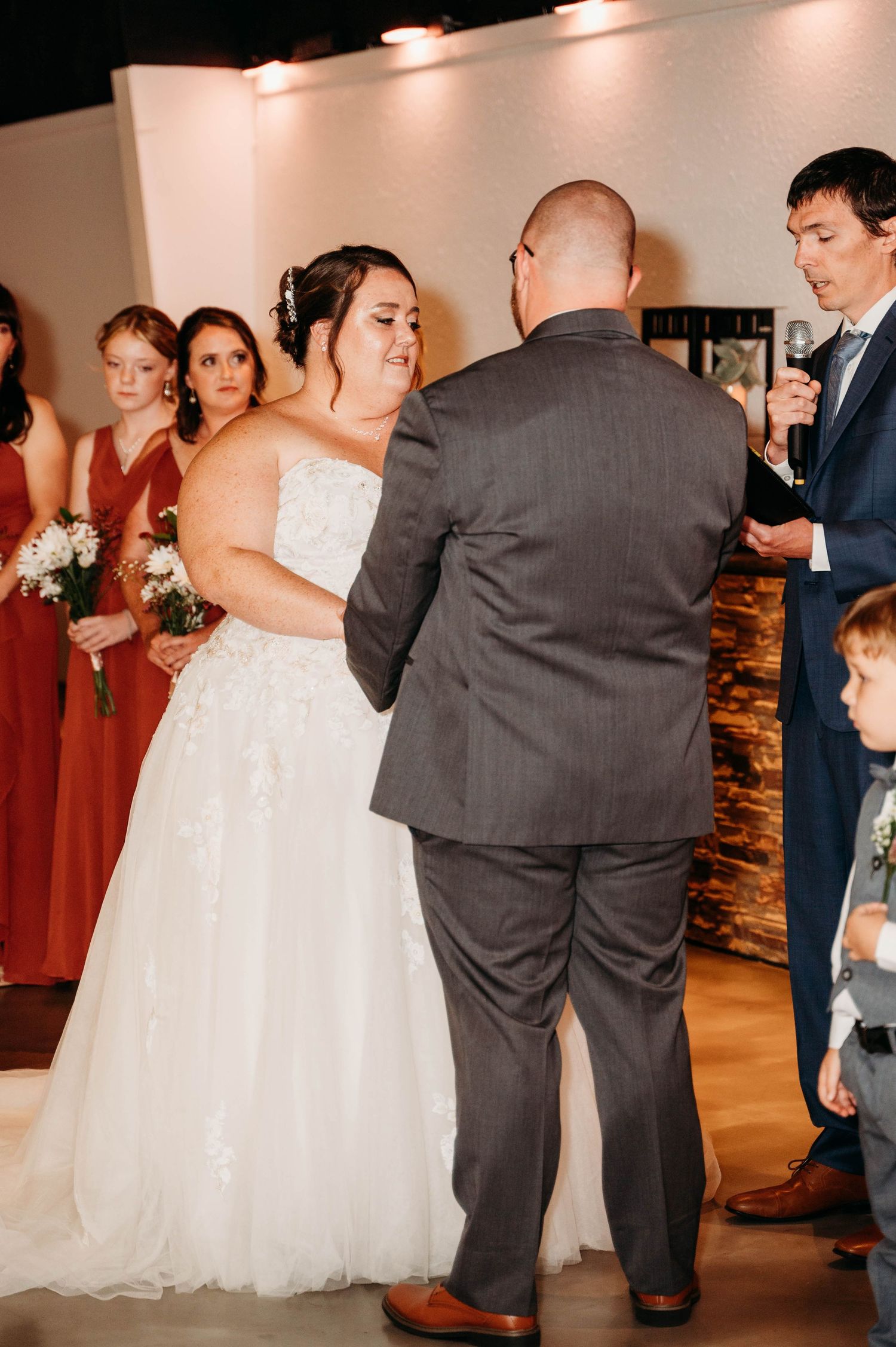 Wedding couple and guests dancing together at an indoor reception venue with warm lighting.