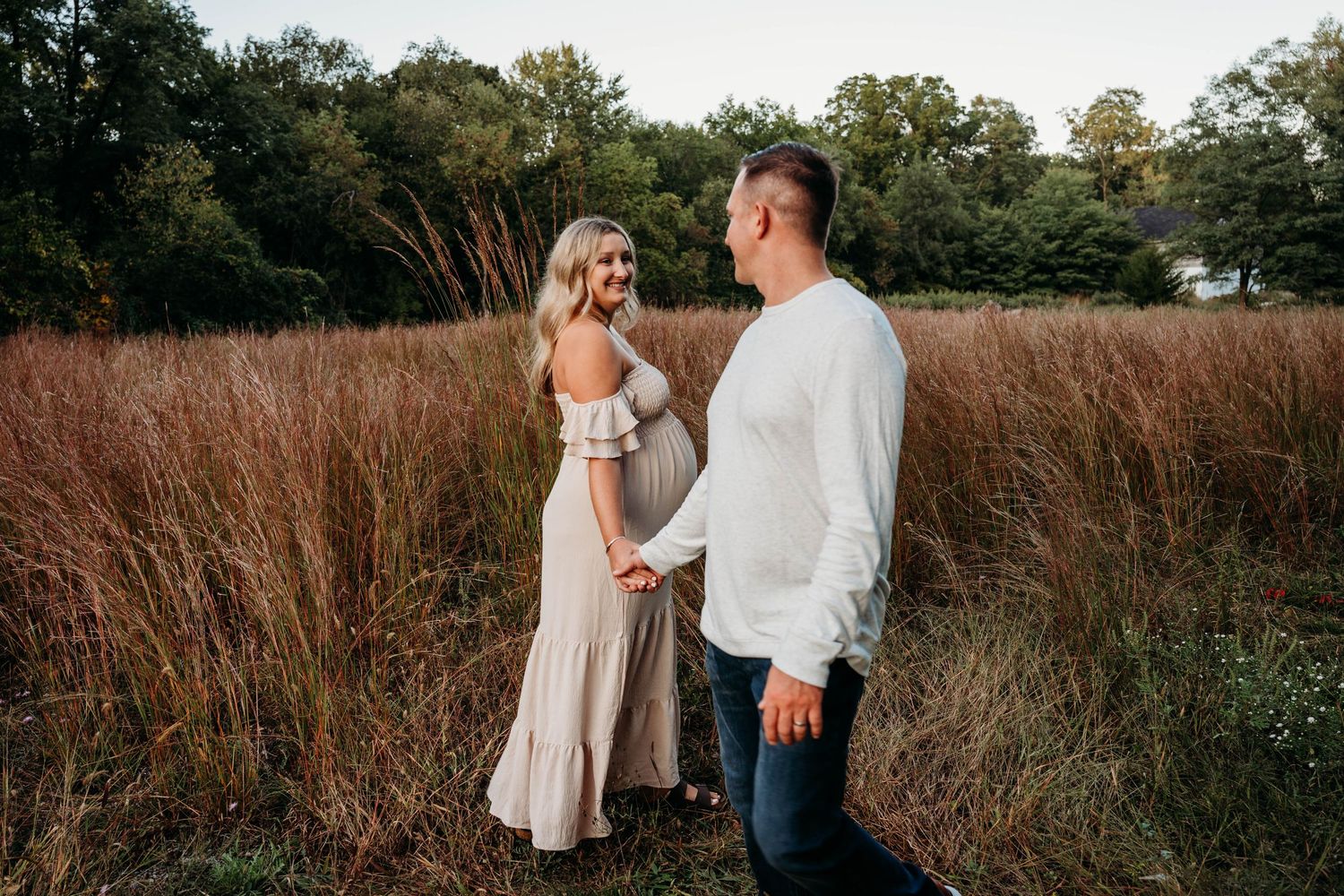 A couple shares an intimate moment in a golden field during sunset.