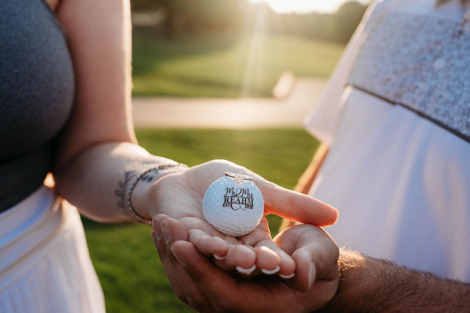 Close-up view of hands holding a baseball with golden sunlight in the background.