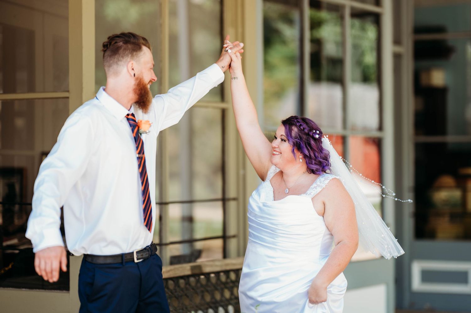 A couple in wedding attire dances together during their first dance at an outdoor venue.