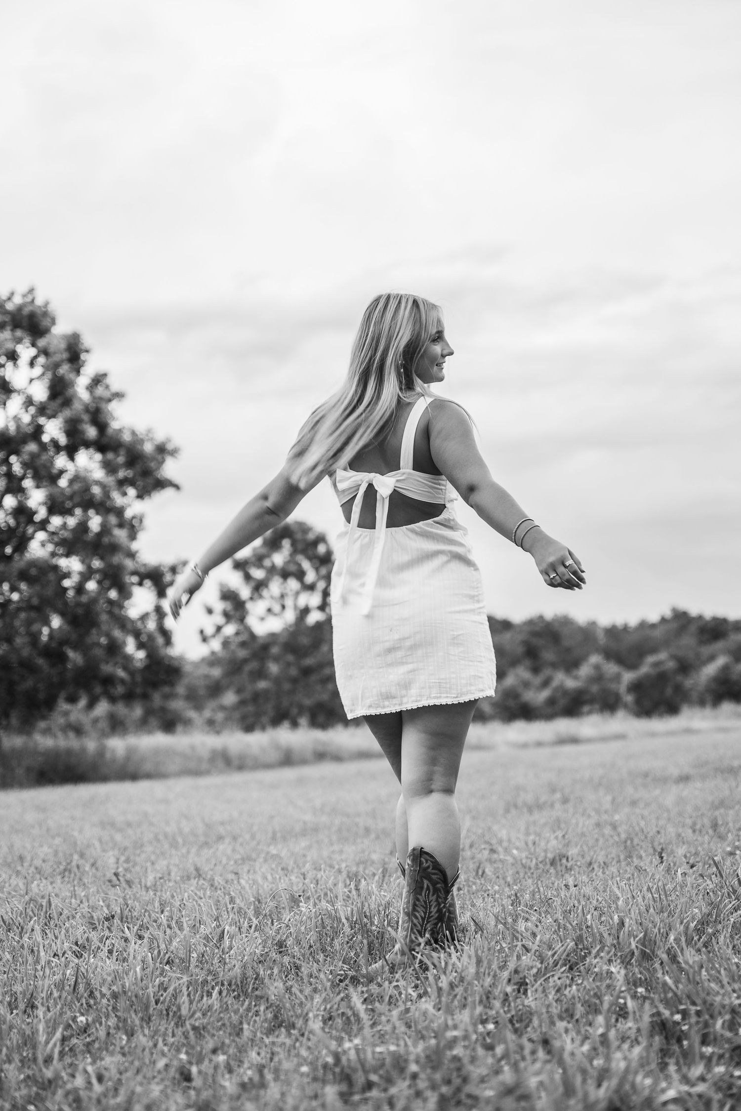 Black and white photos showing someone twirling in a white dress across an open grassy field.
