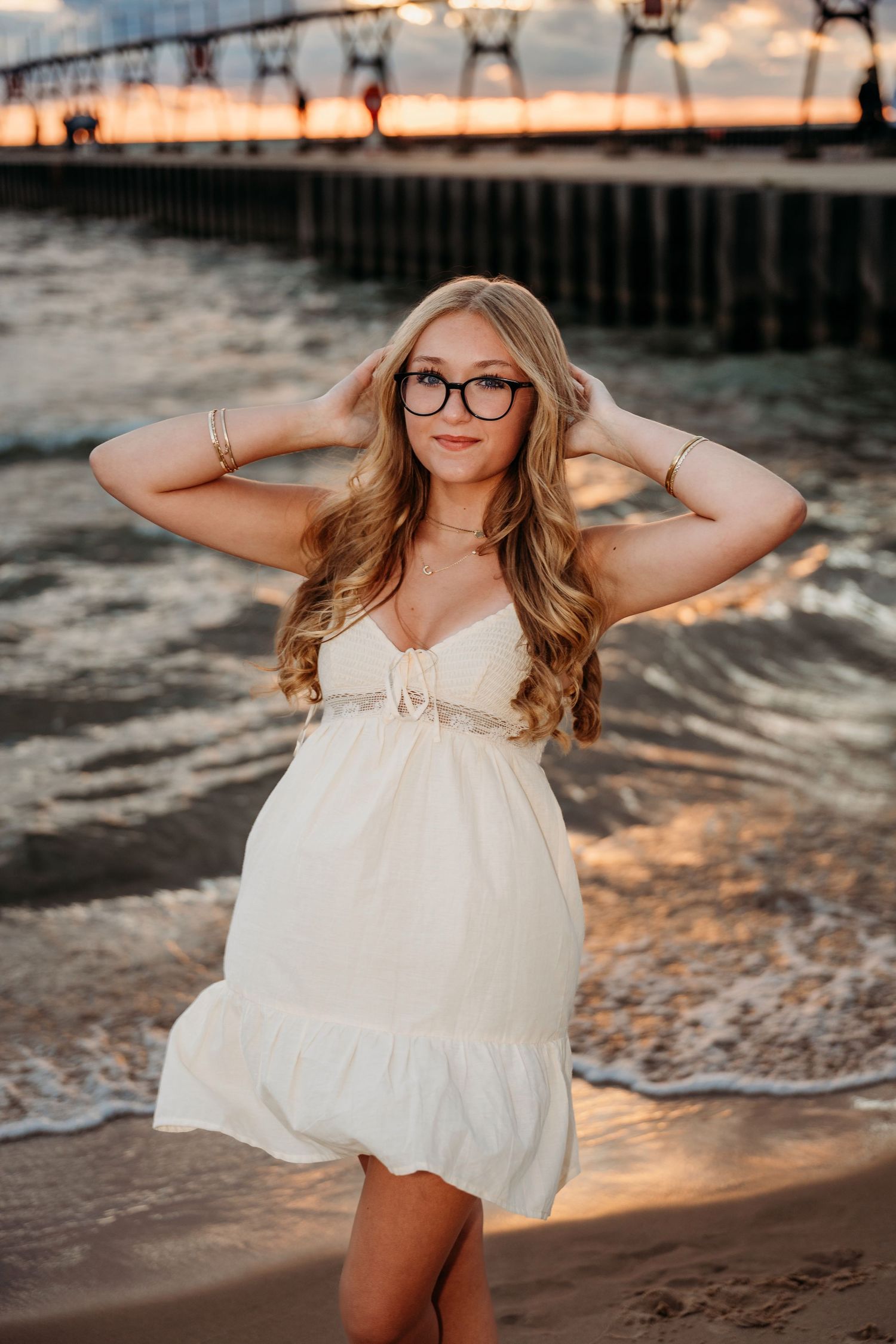 Sunset beach photography session with golden light reflecting off the water and pier in background.