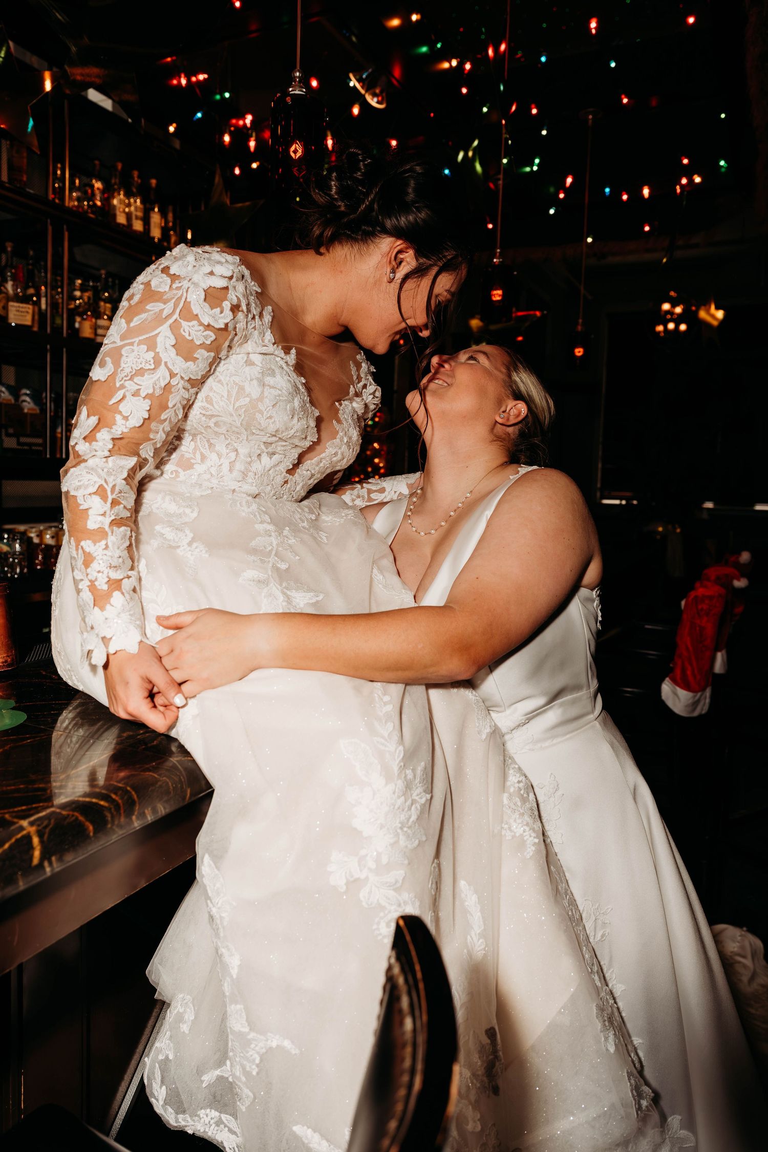 Couple in white wedding attire share an intimate dance moment under twinkling lights.