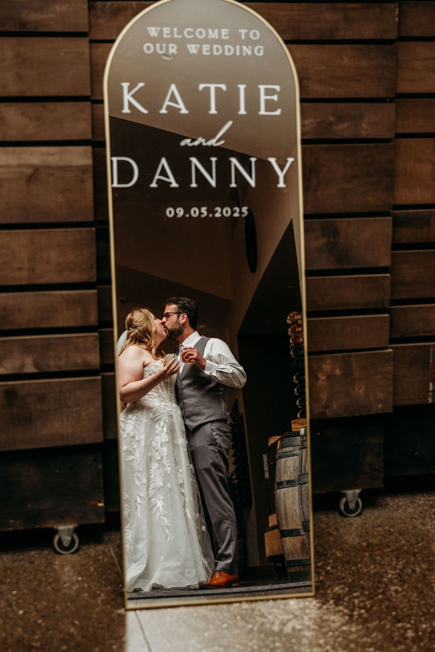 Rustic wedding welcome sign display with wooden panels and elegant lettering against barn wood background.