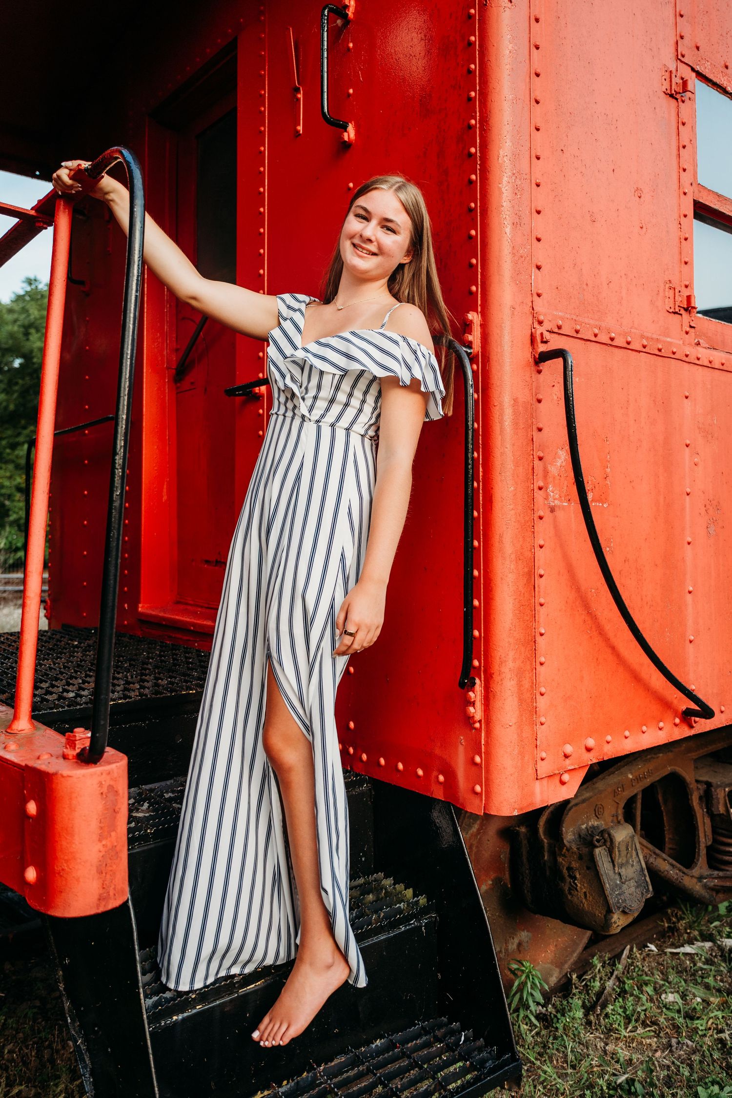 A striped summer dress creates contrast against vibrant red train cars in a series of artistic outdoor photos.