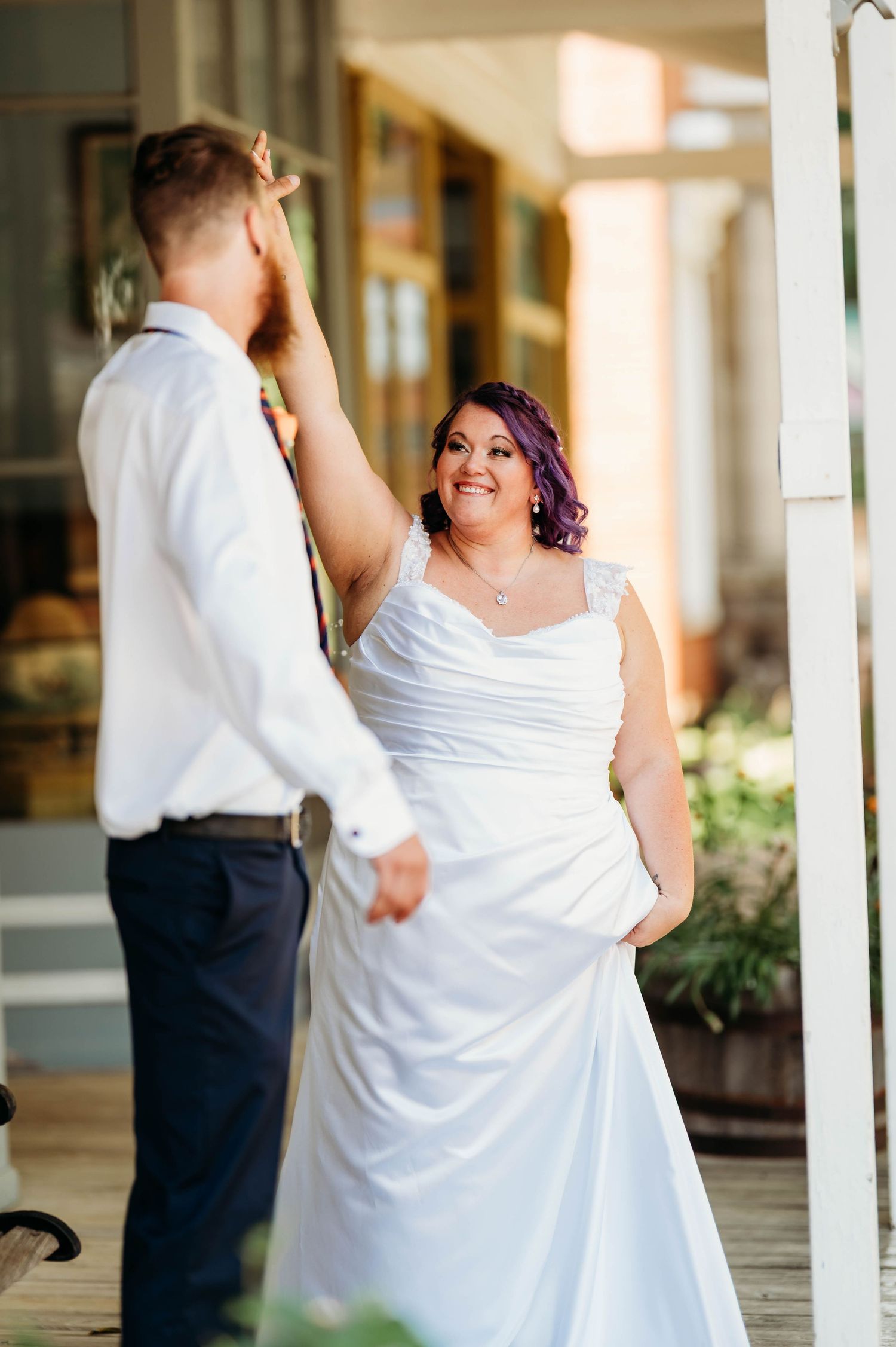 A couple shares a joyful moment during their first dance at their wedding on a covered porch.