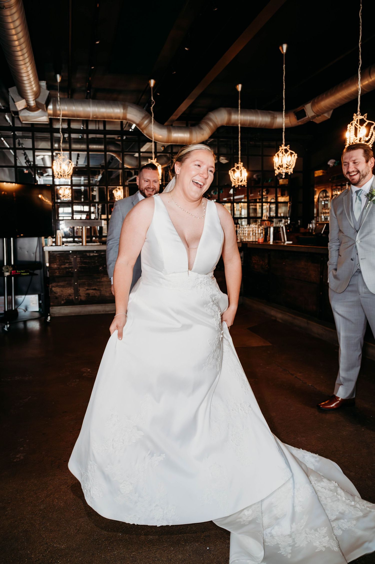 A couple dances together at their wedding reception, with the bride wearing a flowing white gown and the groom in a gray suit.