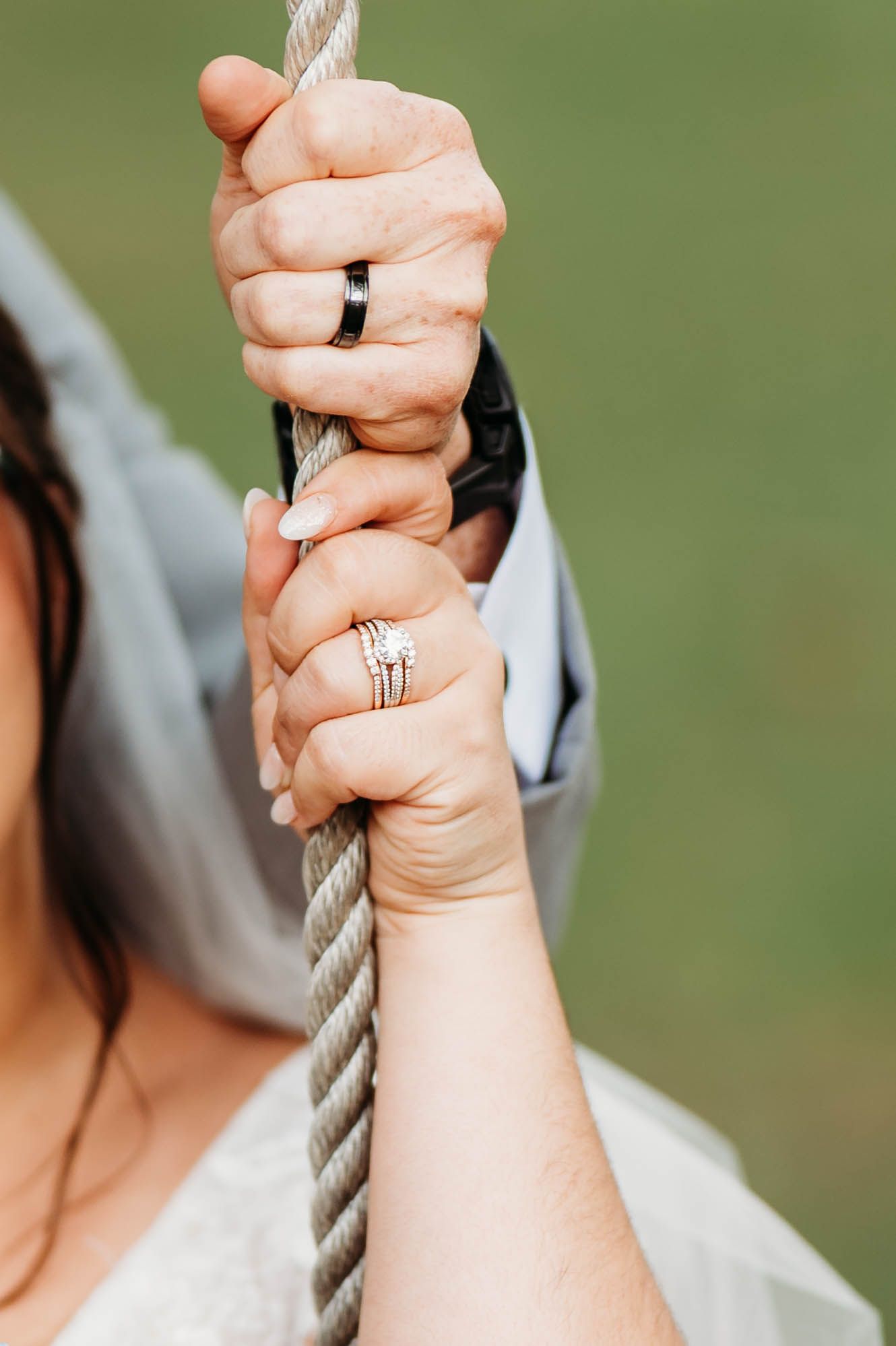 Close-up shots of hands gripping a rope or cable with wedding rings visible against a blurred green background.