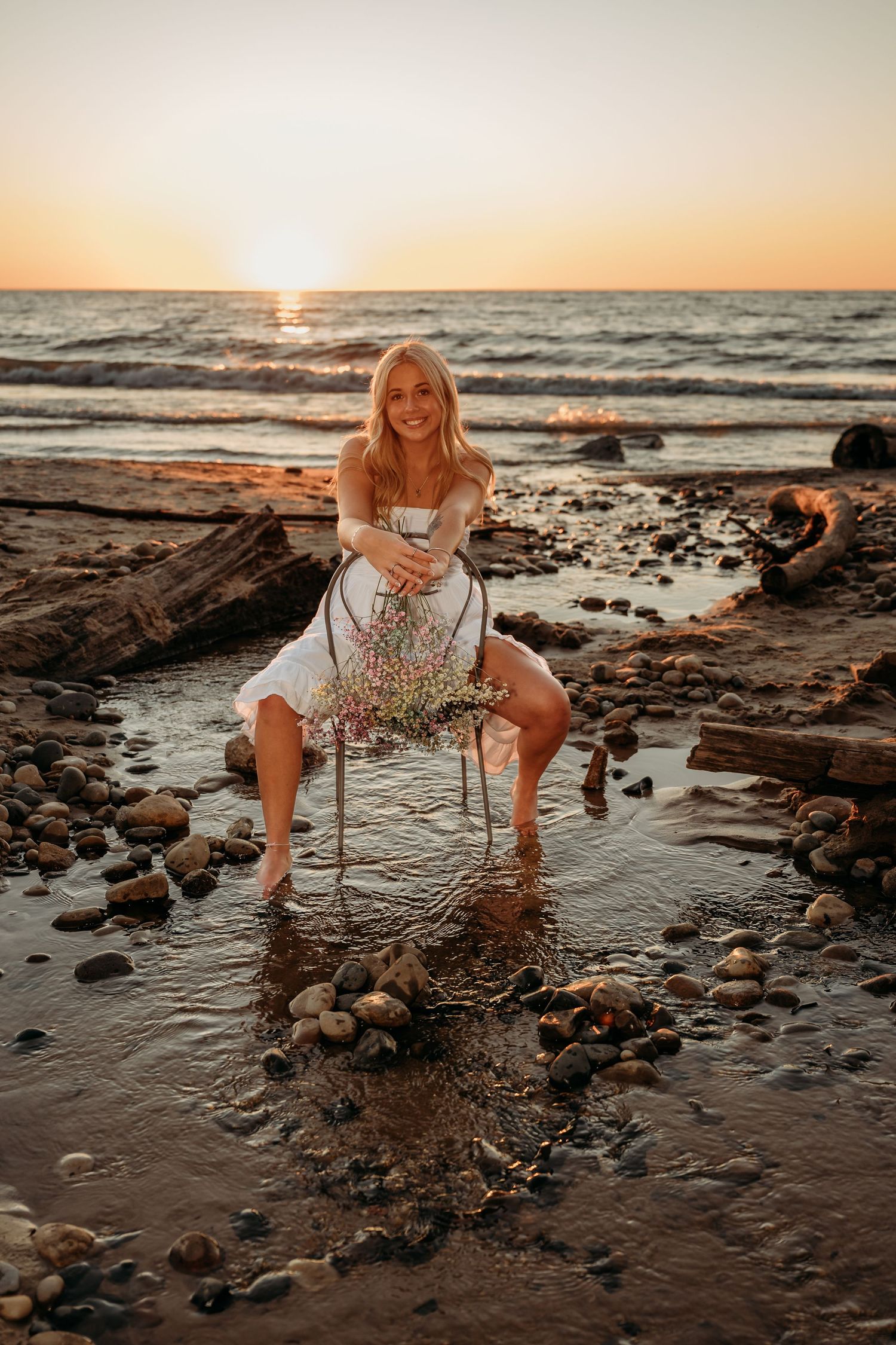 A rocky beach at sunset with waves crashing against the shore and golden light reflecting off the water.