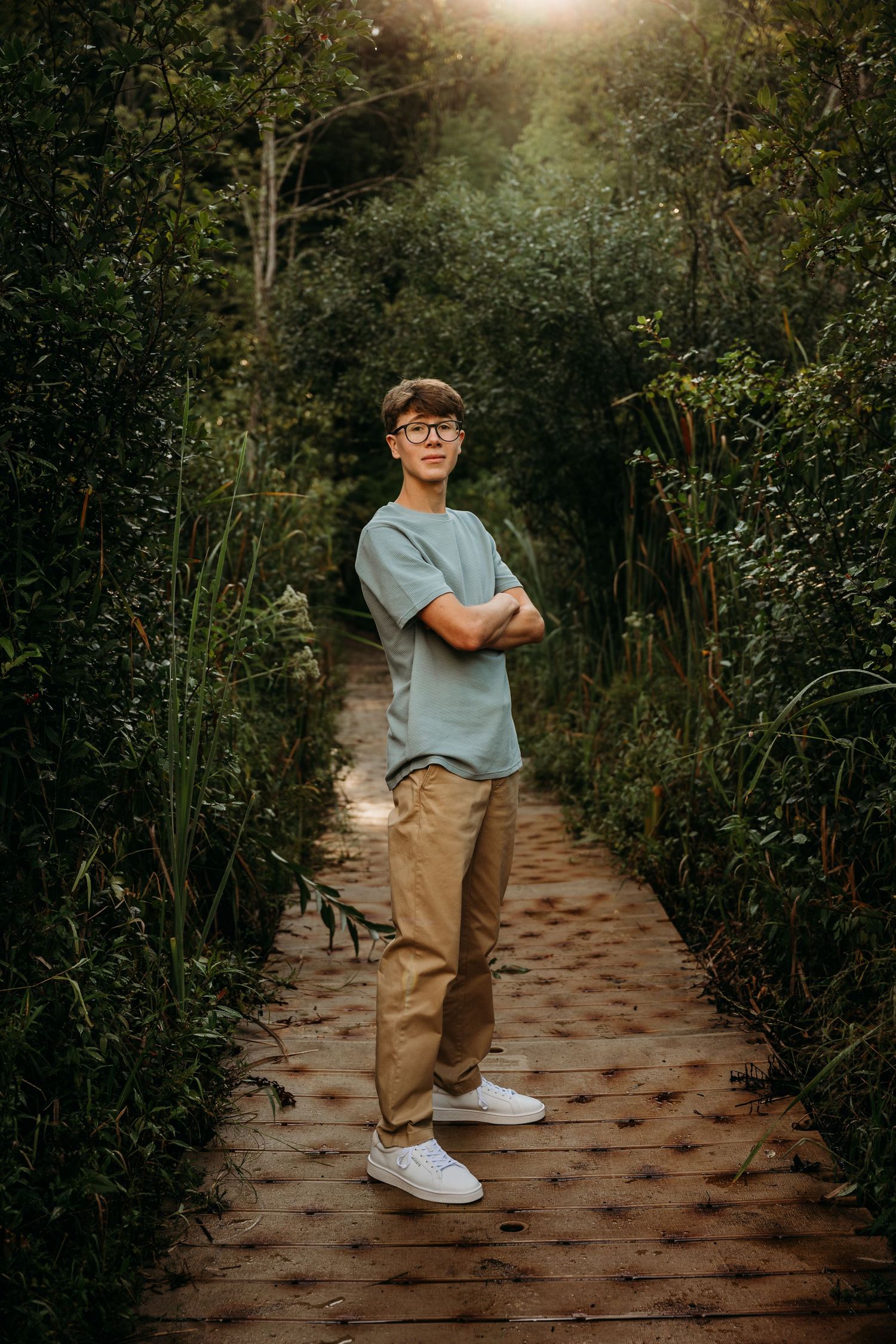 A figure in casual attire dancing playfully along a garden pathway during golden hour lighting.