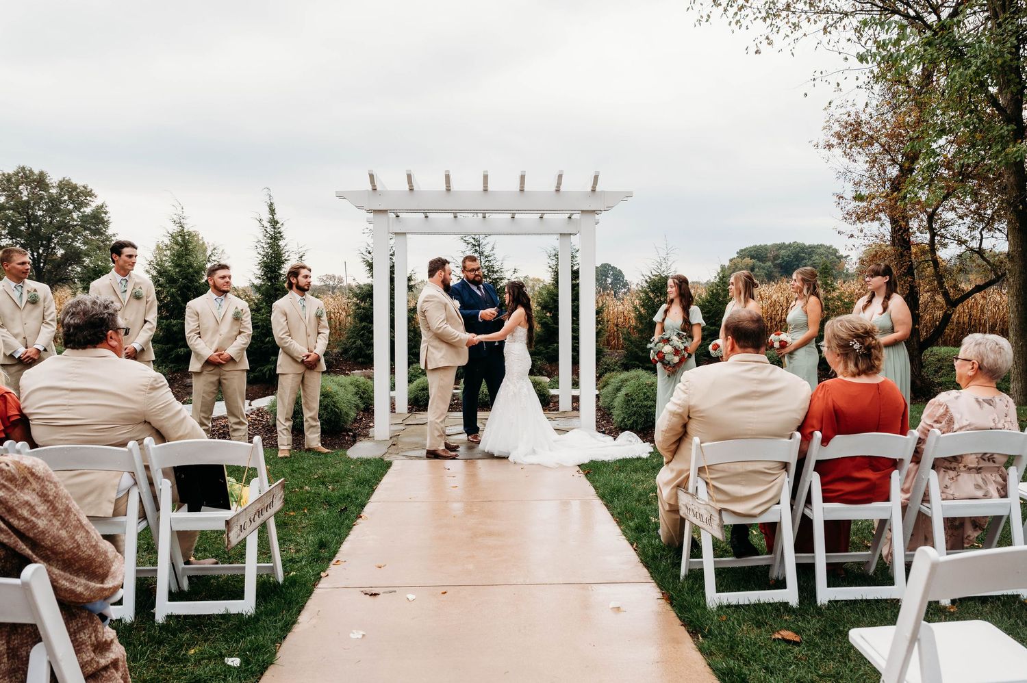 Outdoor wedding ceremony setup with white chairs and floral arch overlooking a scenic waterfront view.