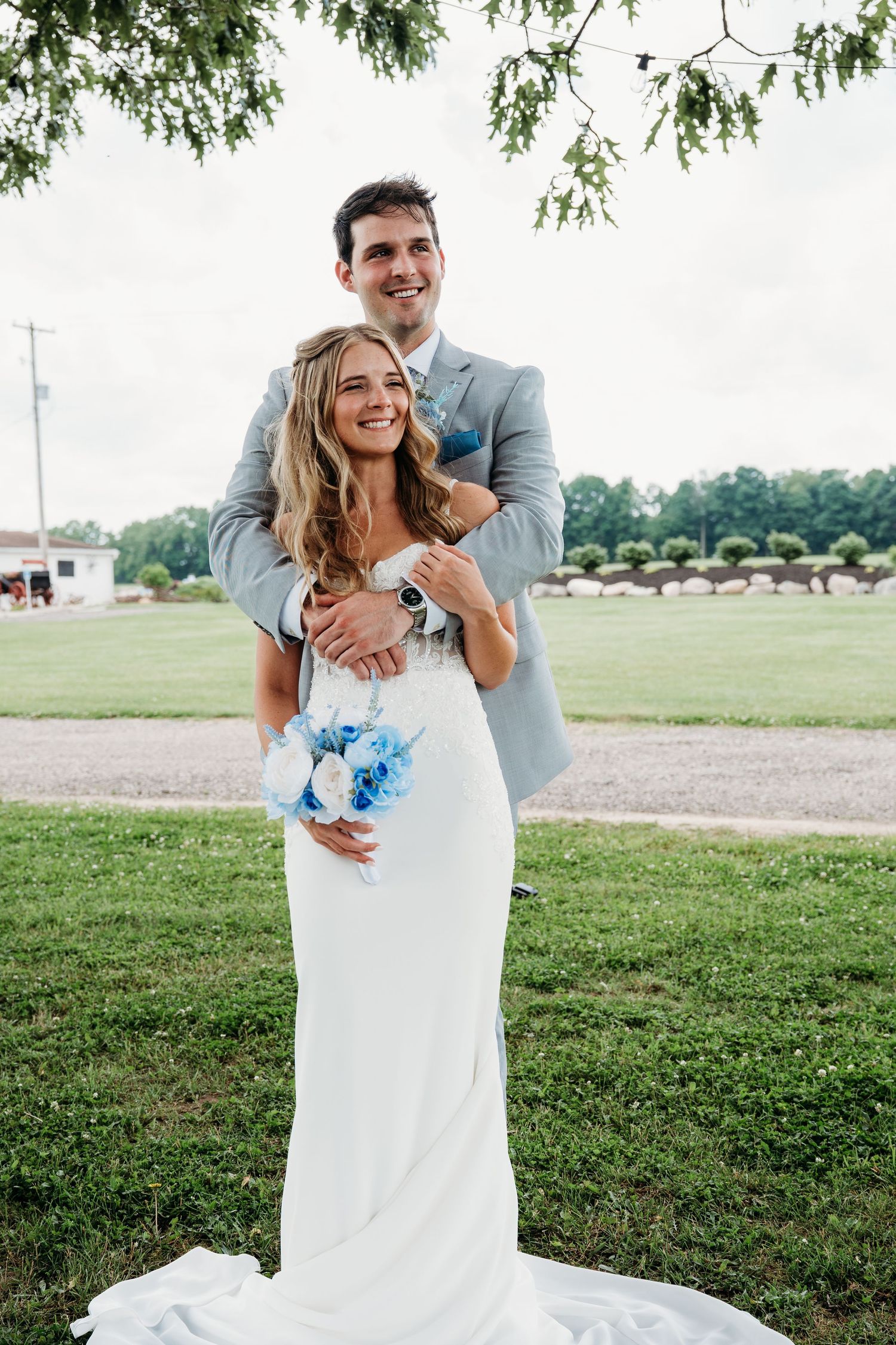 A playful wedding couple shares joyful moments together in a grassy outdoor setting.