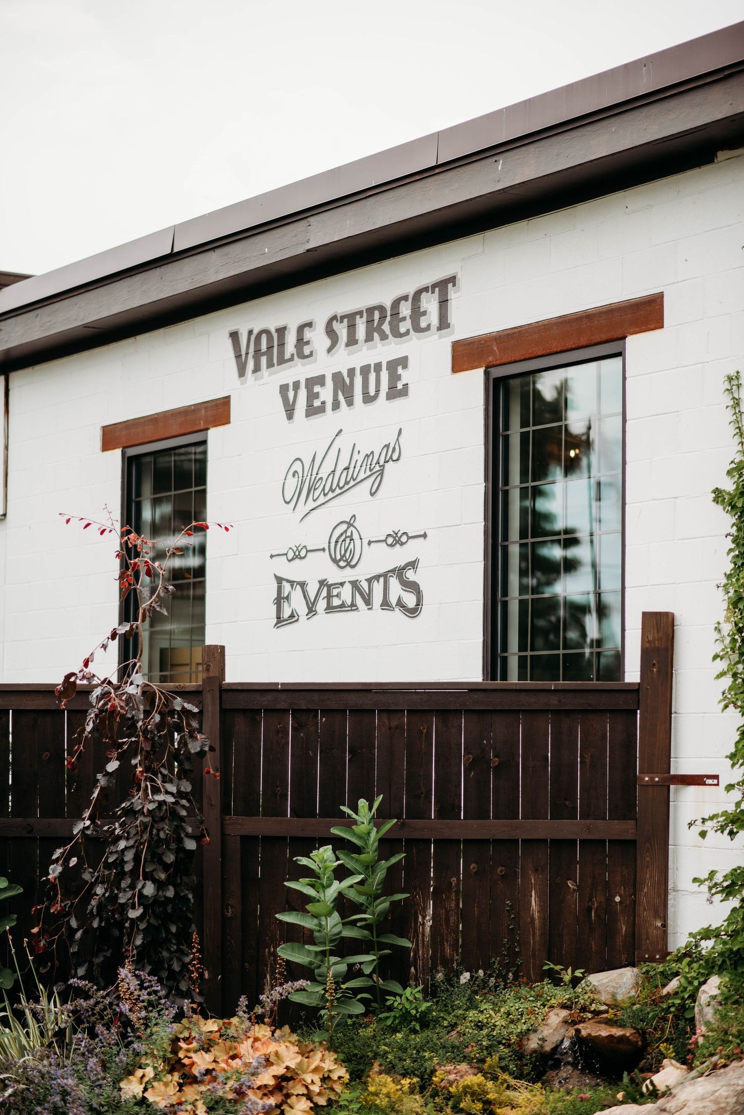White building exterior with 'Vale Street Venue' and 'Weddings & Events' signage above wood paneling and garden landscaping.