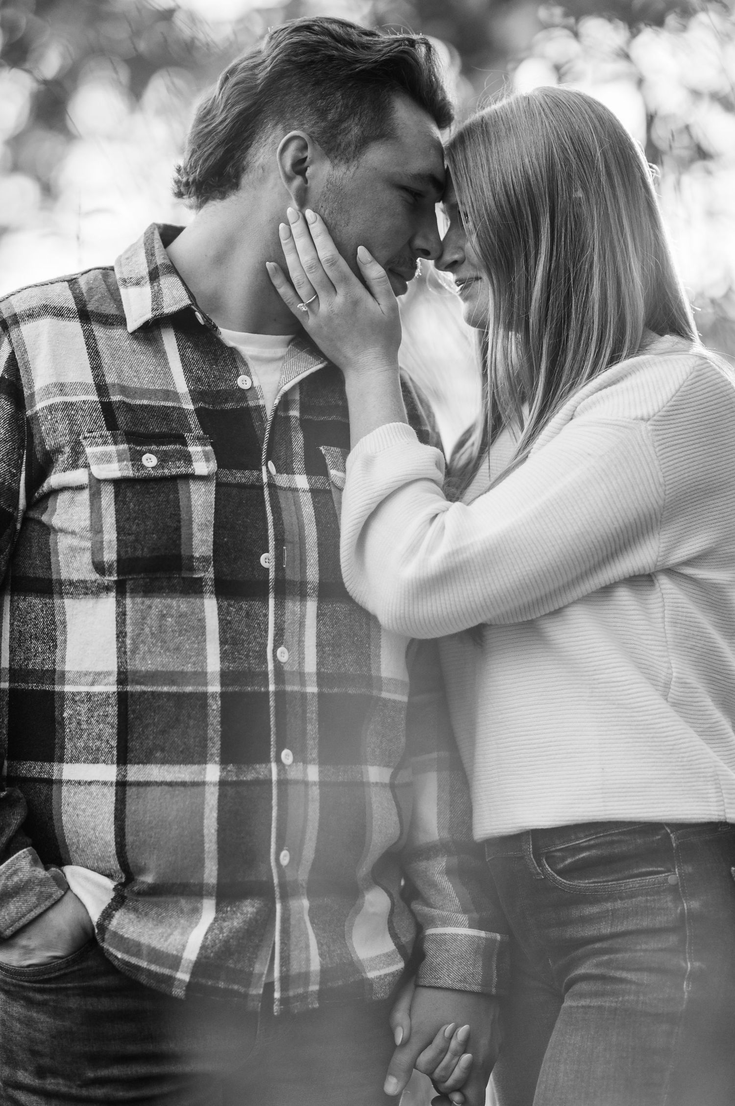 A romantic black and white photo series showing a couple in an intimate embrace wearing casual clothing outdoors.