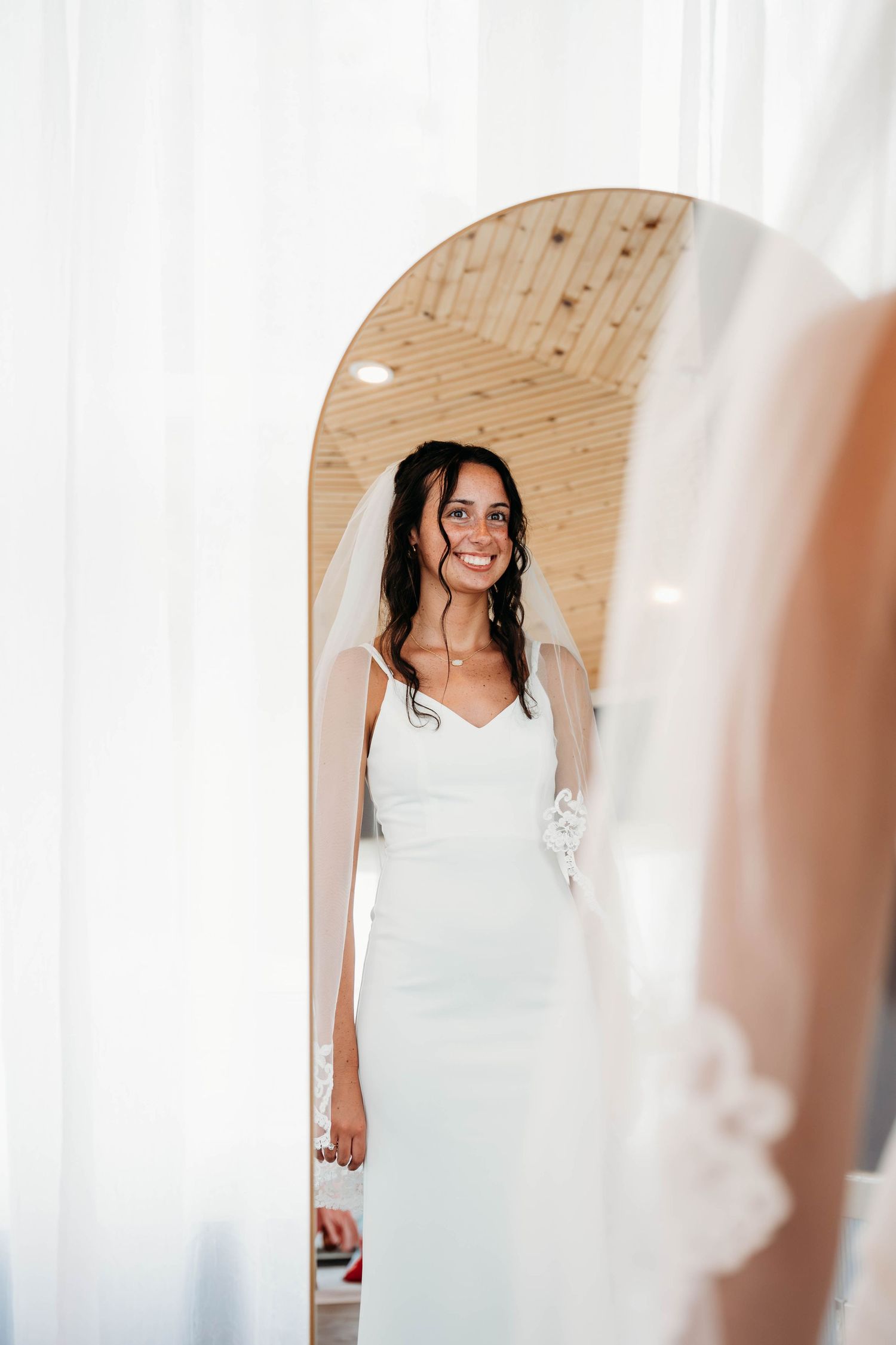 Soft focus view through white curtains showing someone in a white wedding dress.