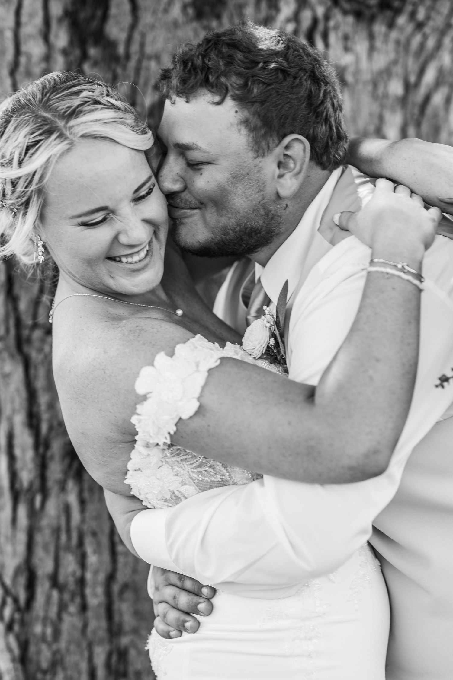 Black and white romantic wedding photos showing tender moments between newlyweds against a rustic backdrop.