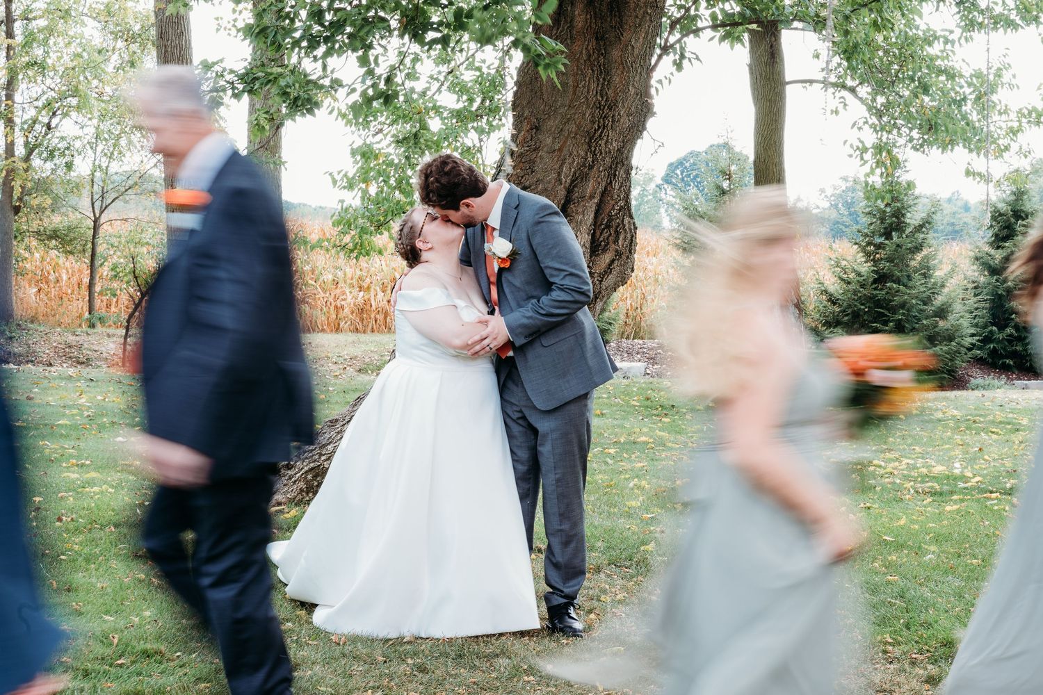 Wedding party members in formal attire dance and celebrate outdoors during a festive reception gathering.