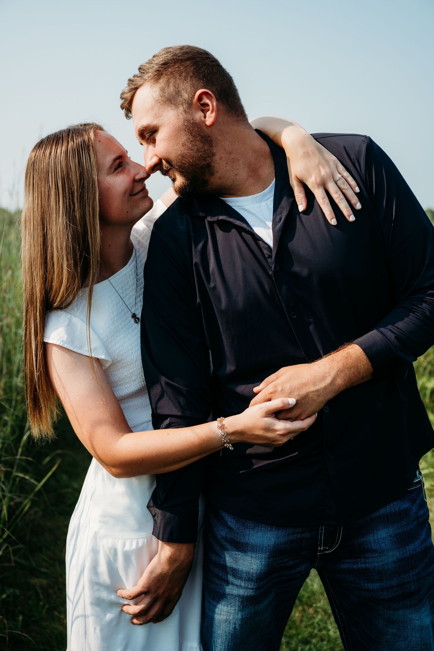 A romantic couple in white and dark clothing embraces and shares intimate moments in an outdoor setting.