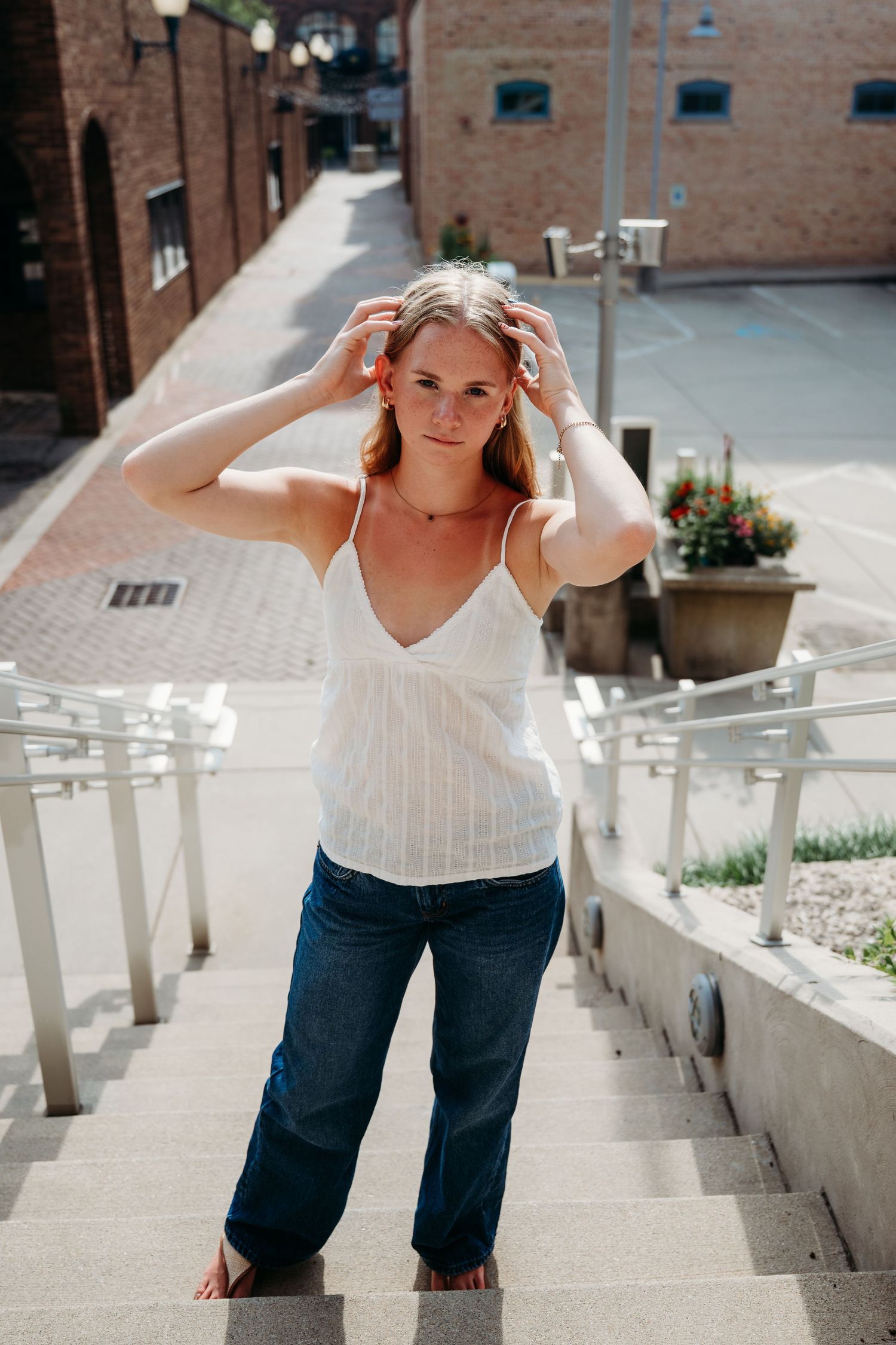A progression of photos shows a woman in a white top and jeans walking up concrete stairs with brick buildings behind.
