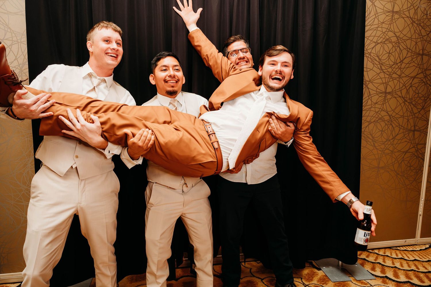 Groomsmen in light colored suits striking fun poses for a group photo.