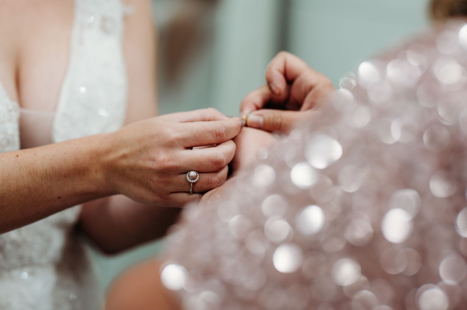 A sequence of hands exchanging rings during a wedding ceremony with soft bokeh lights in the background.