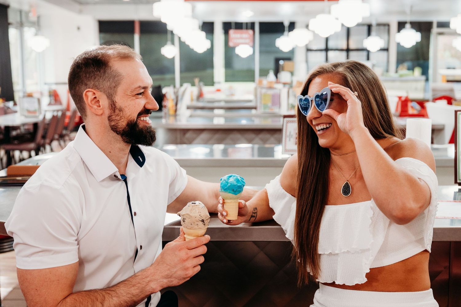 A couple enjoying ice cream and sharing a playful moment at a retro-style diner.