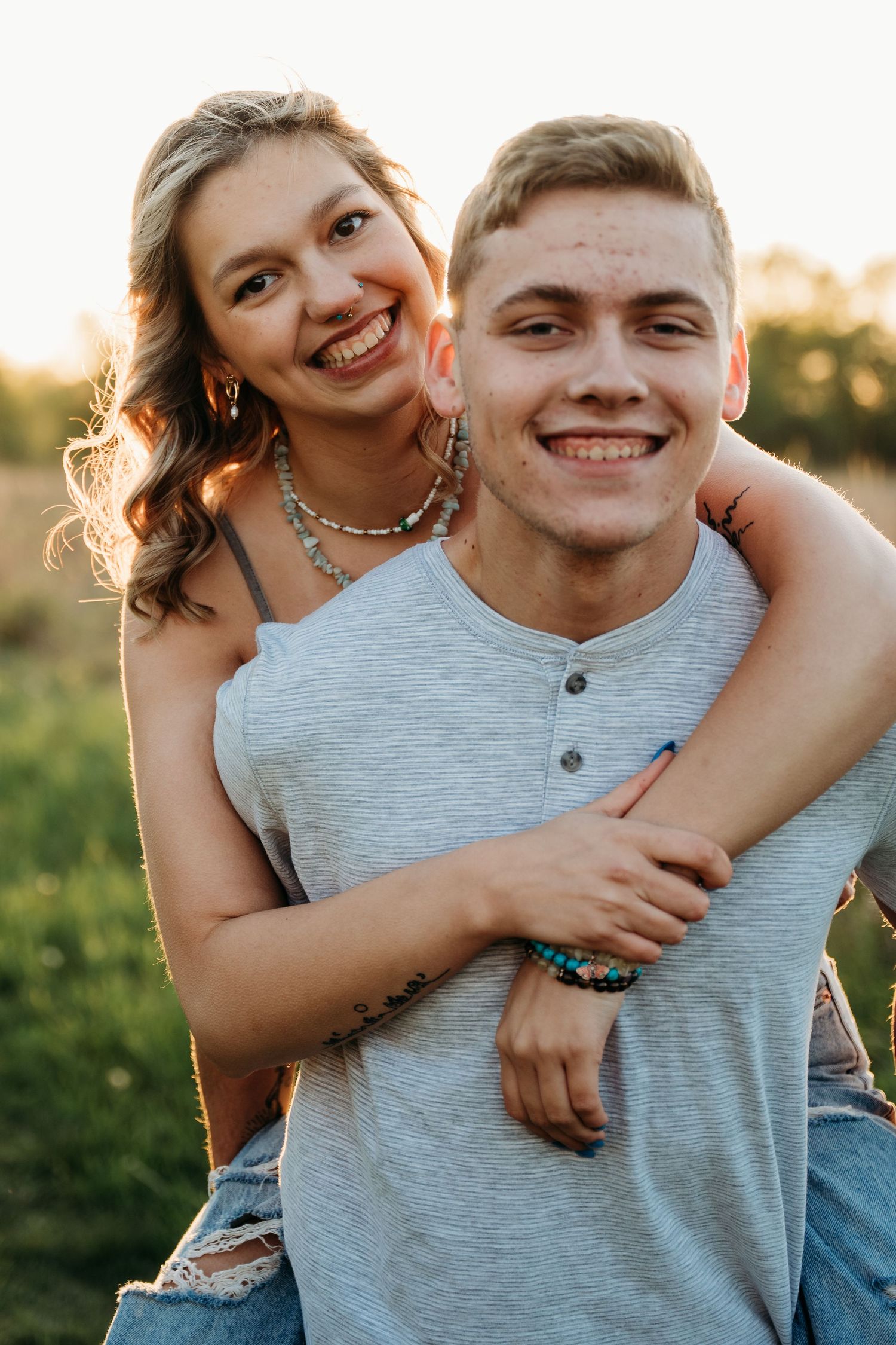 A joyful couple embraces outdoors during golden hour while sharing genuine laughter and smiles.