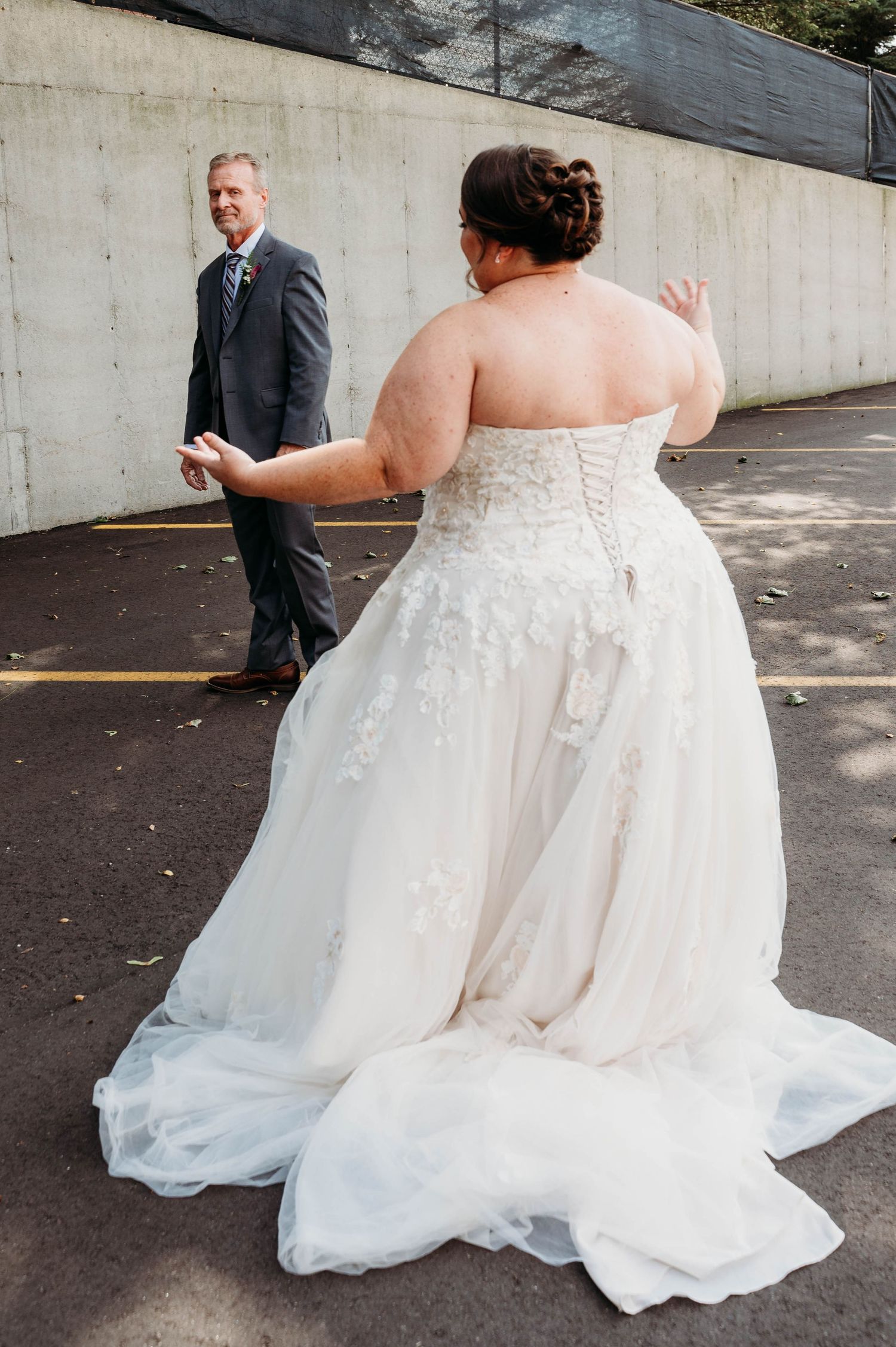 A couple shares their first look moment at a wedding, with the bride wearing a beautiful white lace strapless gown.