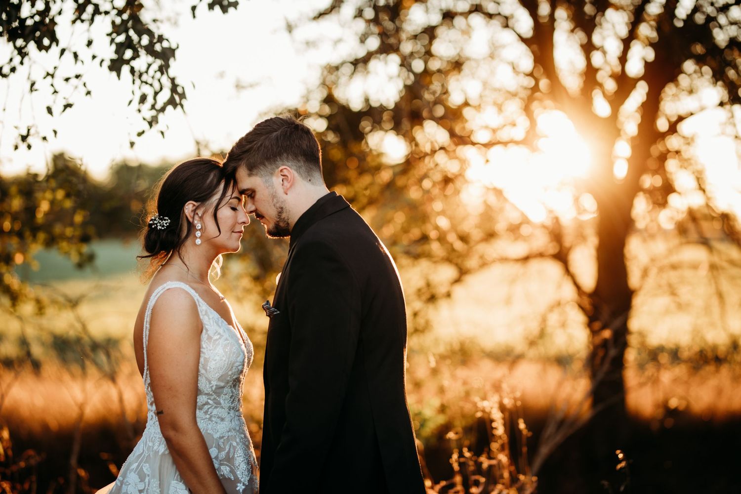 Romantic sunset wedding portrait silhouetted against golden evening light.