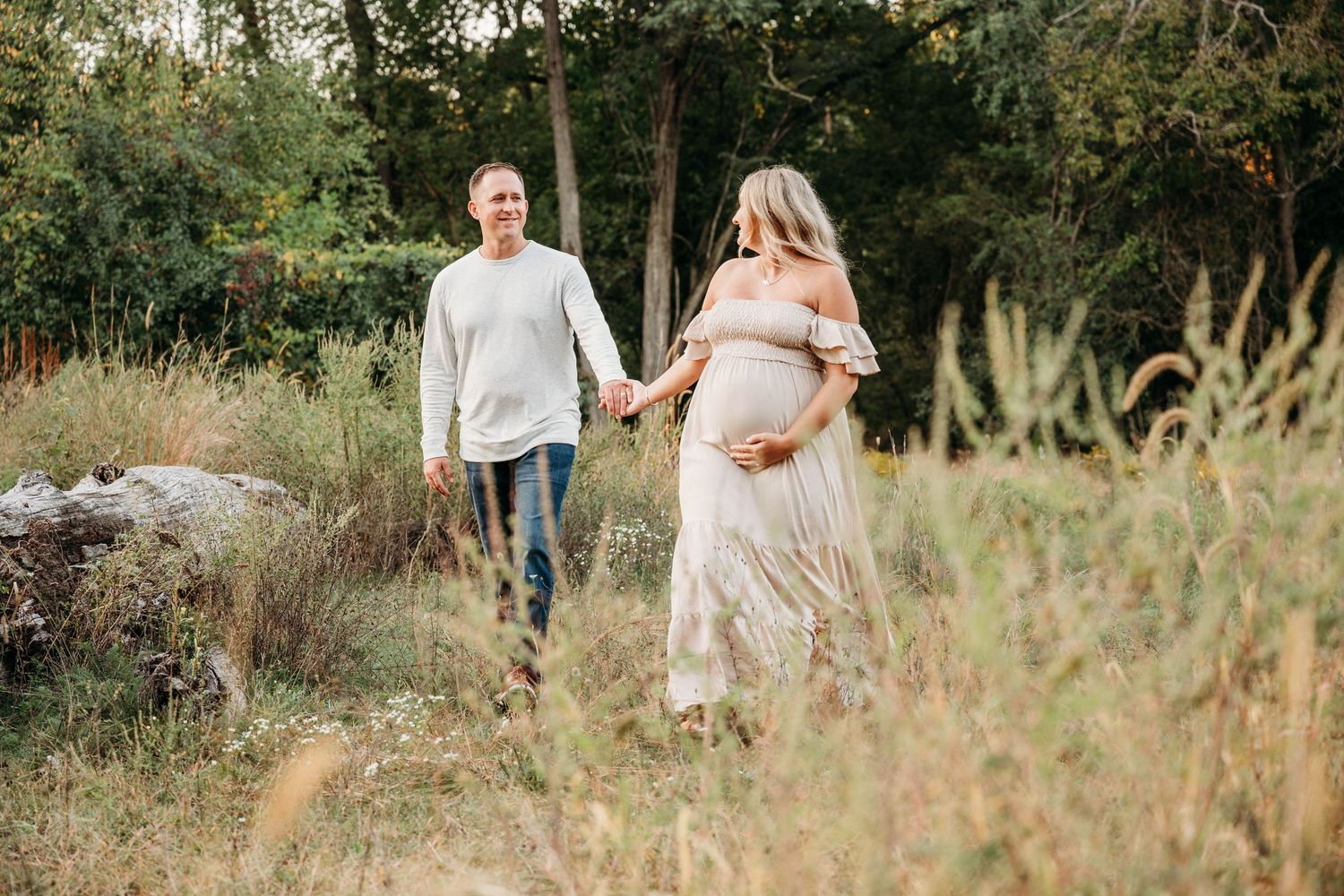 A romantic maternity photo session in a rustic field with tall grass and natural lighting.