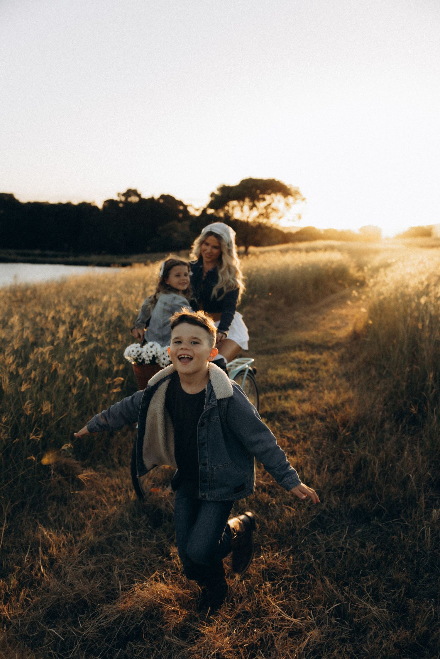 Children running and playing in a grassy field during golden hour.