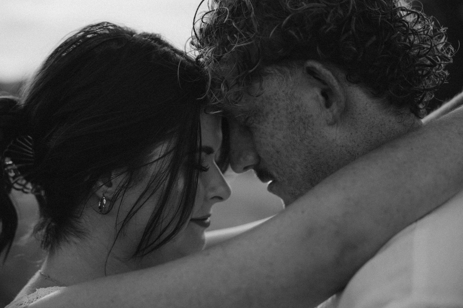 Intimate black and white close-up of couple sharing tender moment.