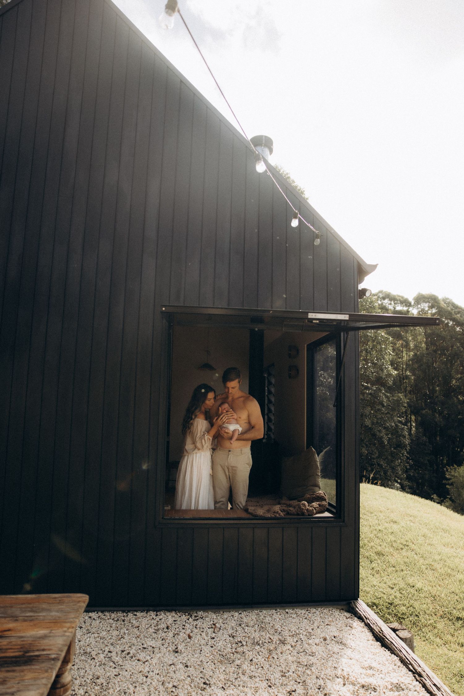 Dark wooden building exterior with figures visible through a window opening.