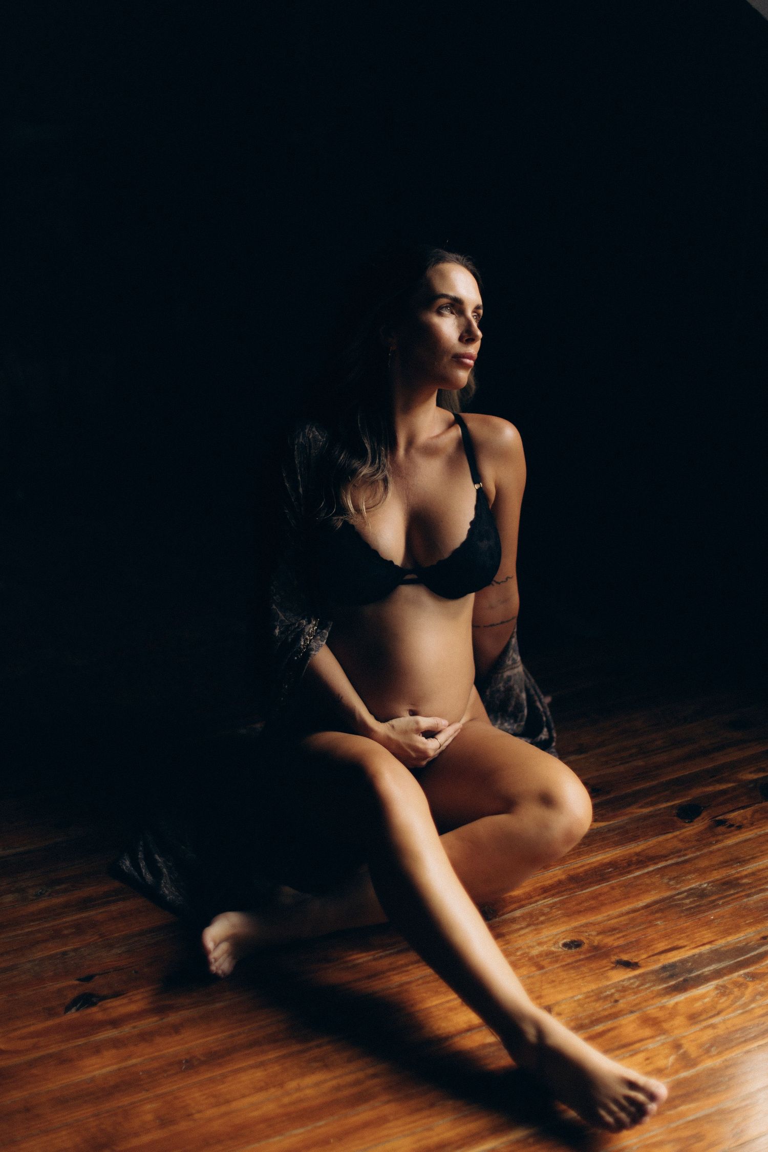 Artistic portrait on wooden floor with dramatic shadows and lighting.