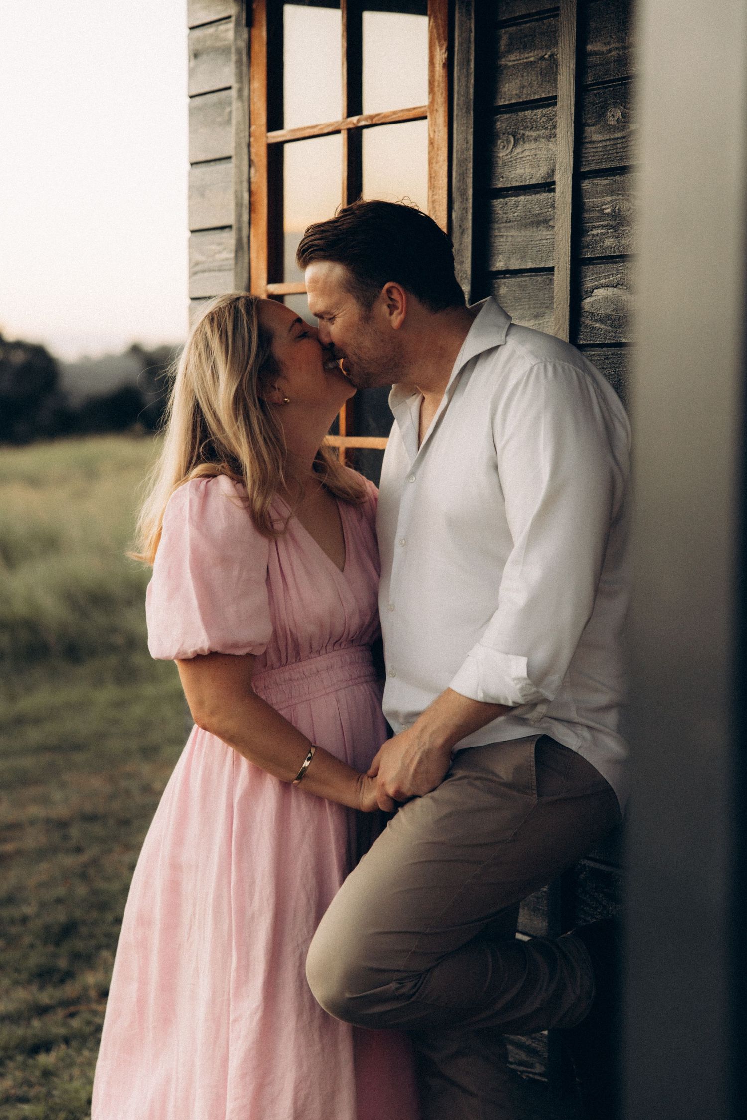 Romantic couple shares intimate moments against rustic wooden walls.