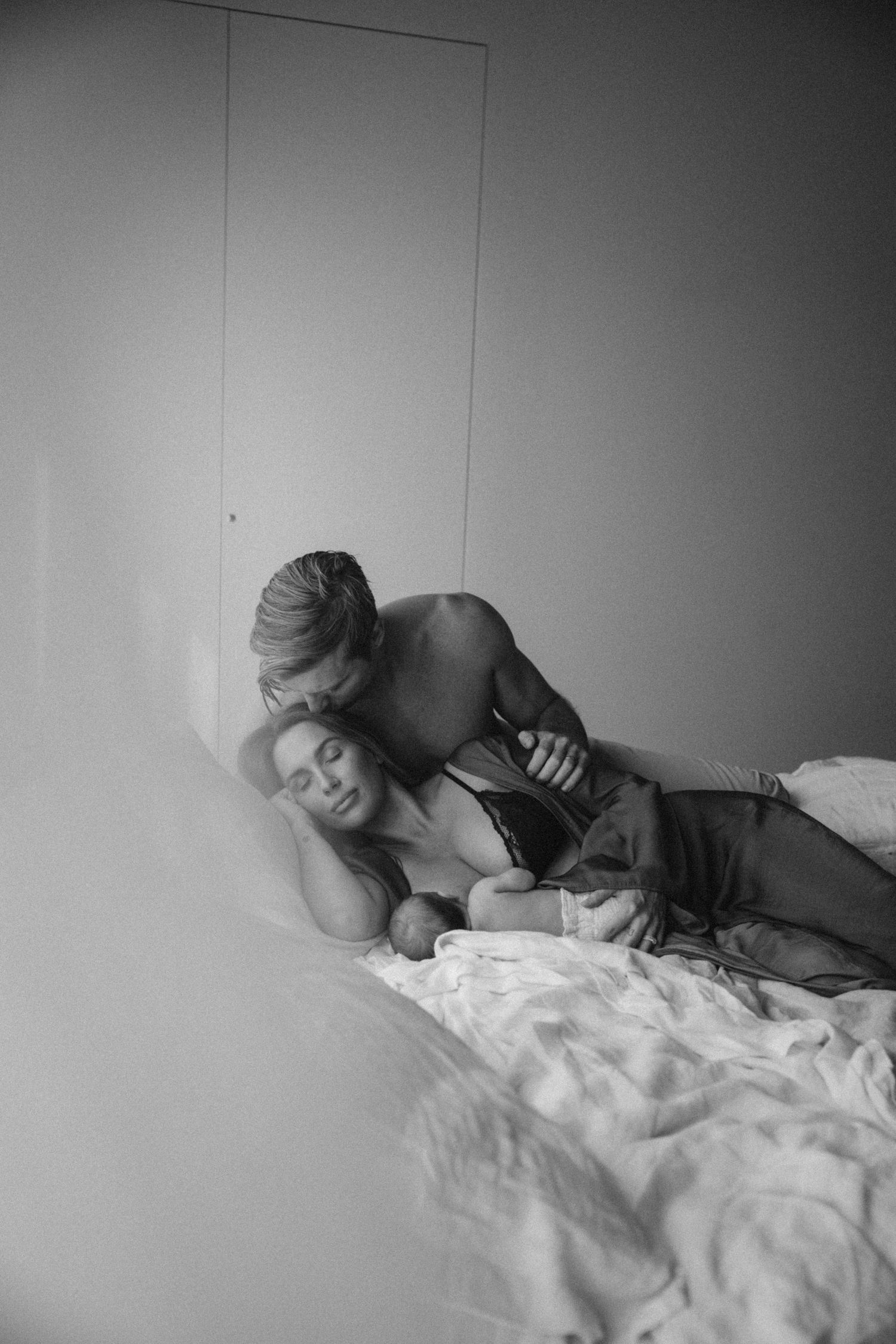 Black and white photograph of two people lying close together on a bed.