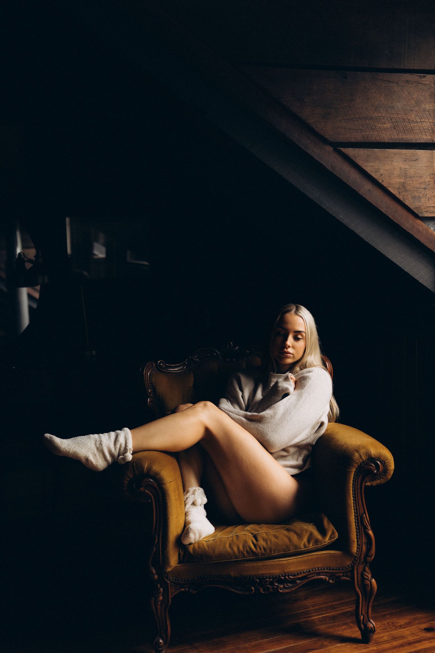 Artistic boudoir photo of a figure reclining on a vintage brown leather couch.