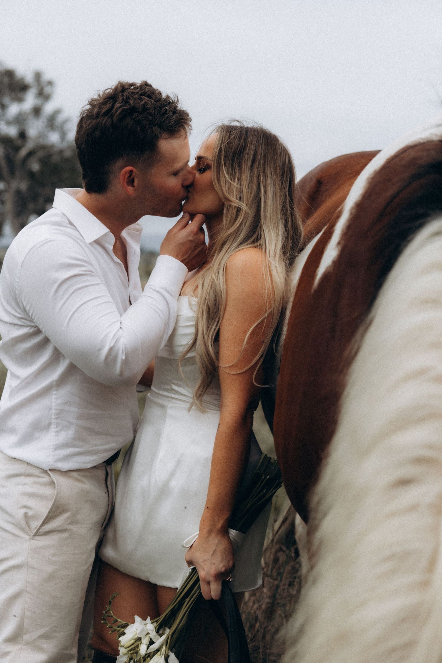 Romantic wedding couple sharing intimate moments beside their horse.