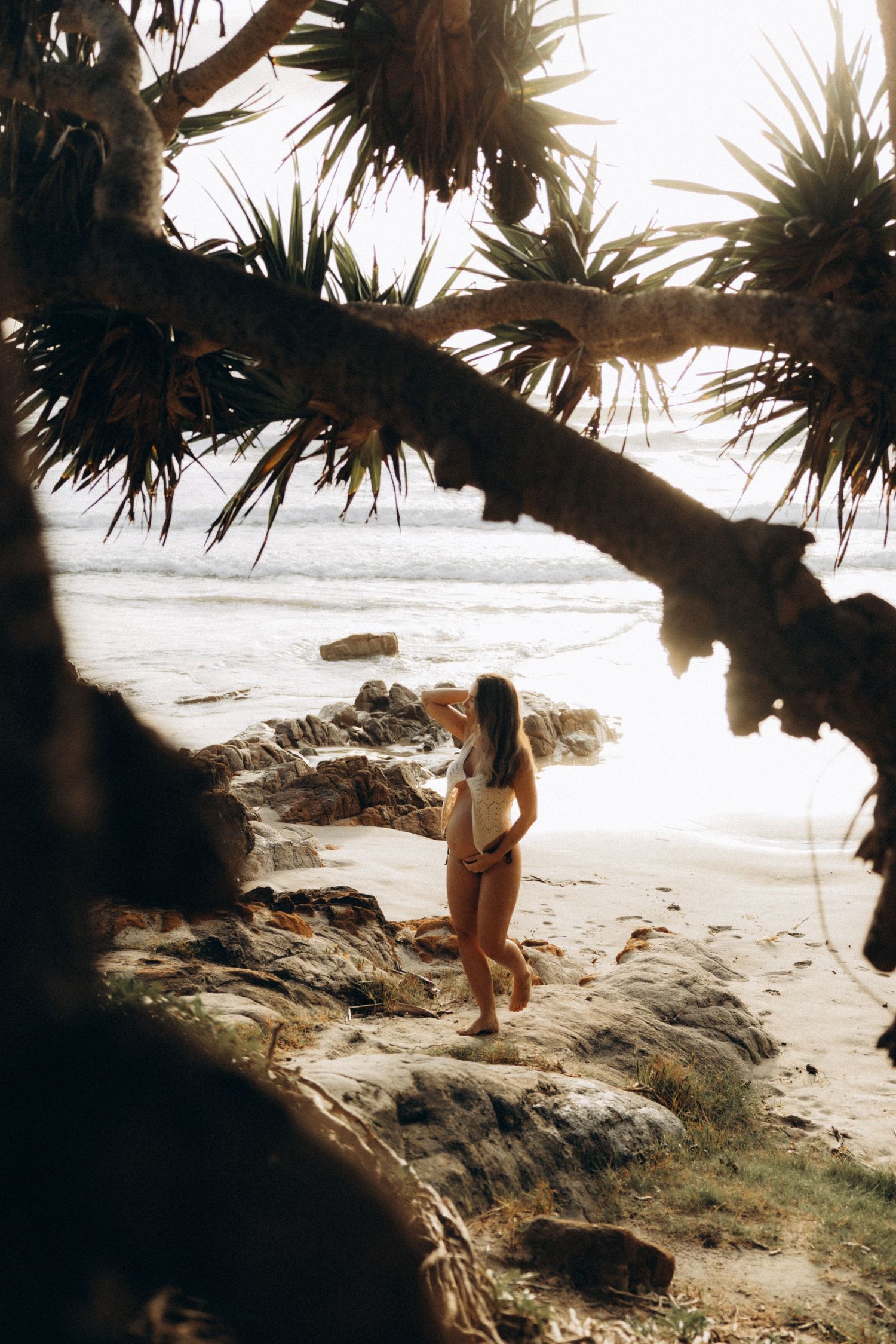 Silhouette beneath palm trees on a rocky tropical beach.
