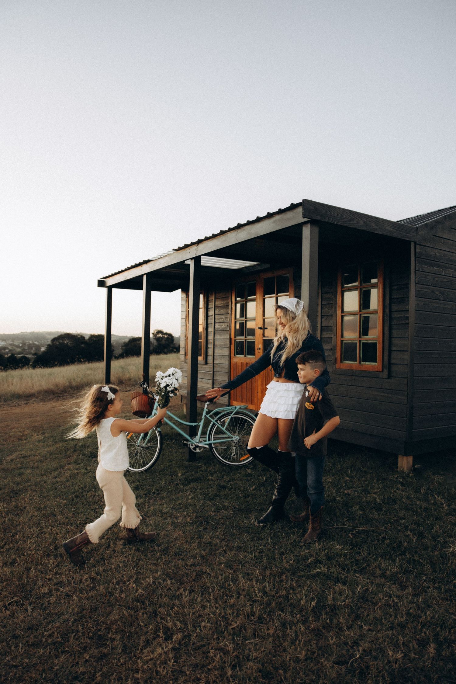 People relaxing outside rustic wooden cabins at dusk.