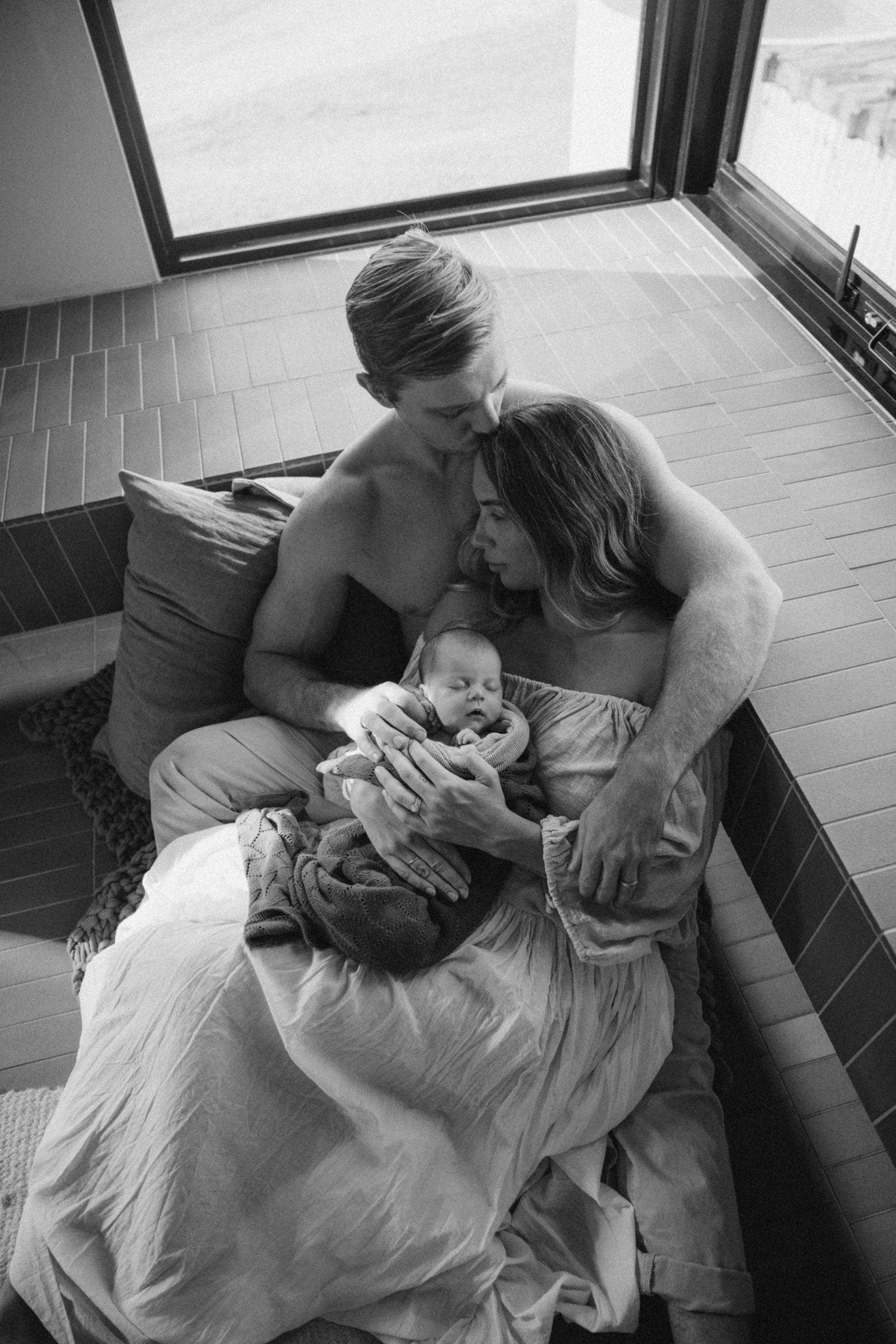 Black and white photographs showing gentle moments of connection and rest on a couch.