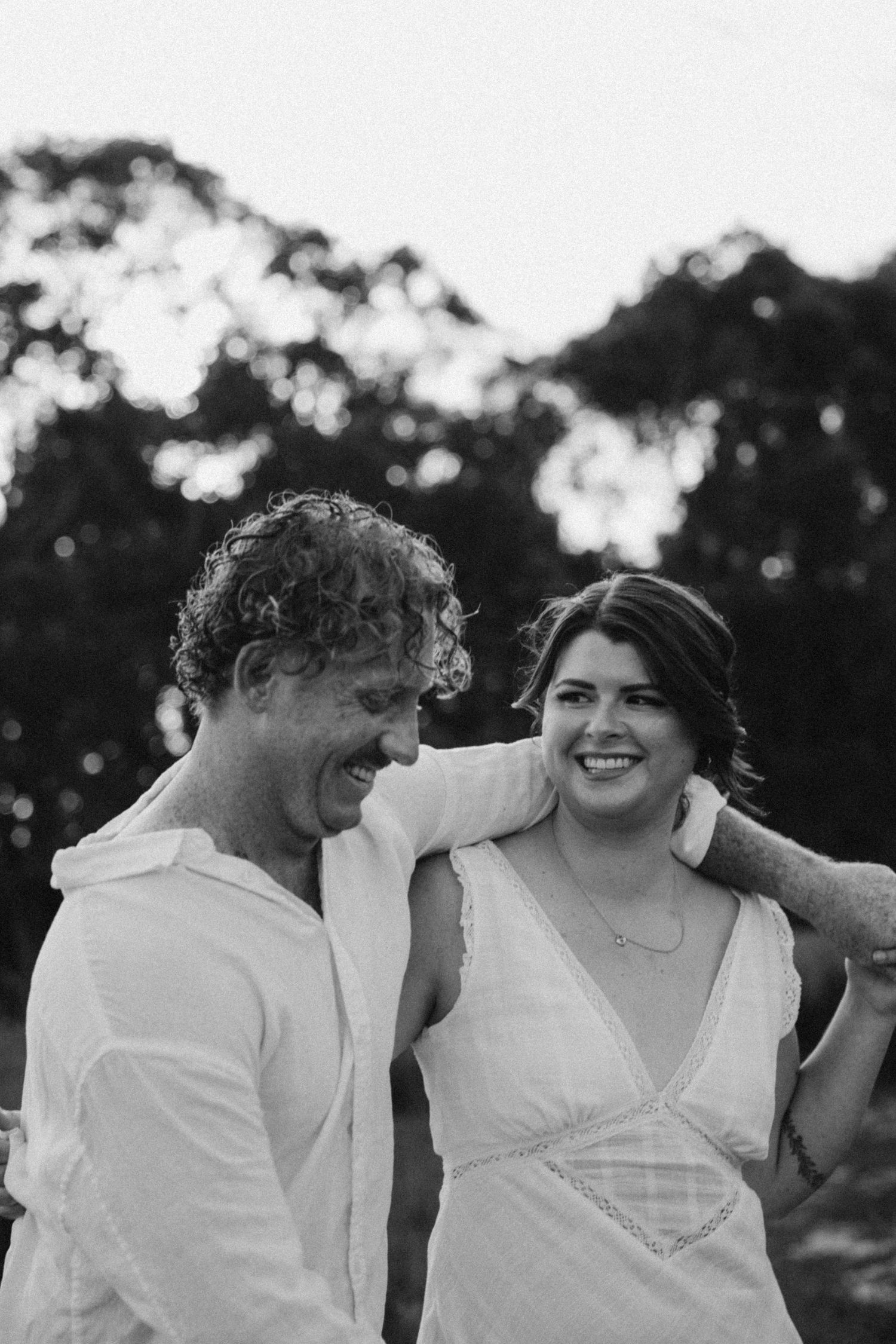 Black and white portrait of a couple sharing a joyful moment outdoors.