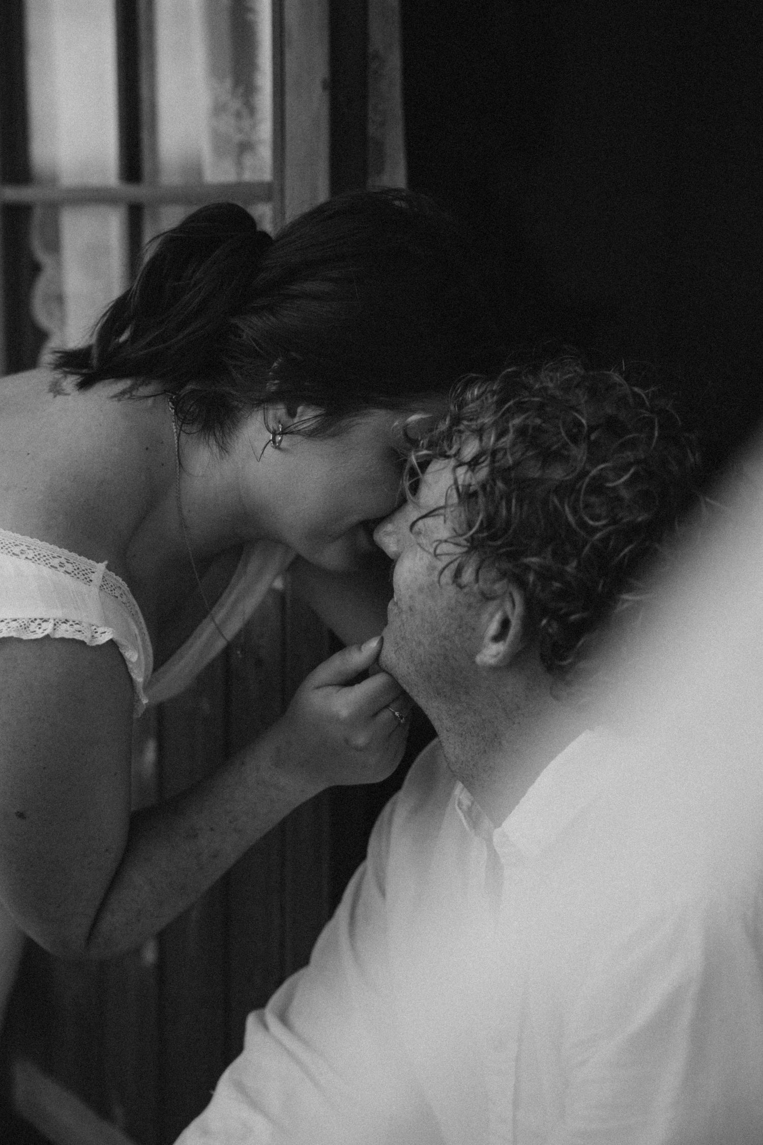 An intimate black and white portrait of a couple sharing a close moment together.