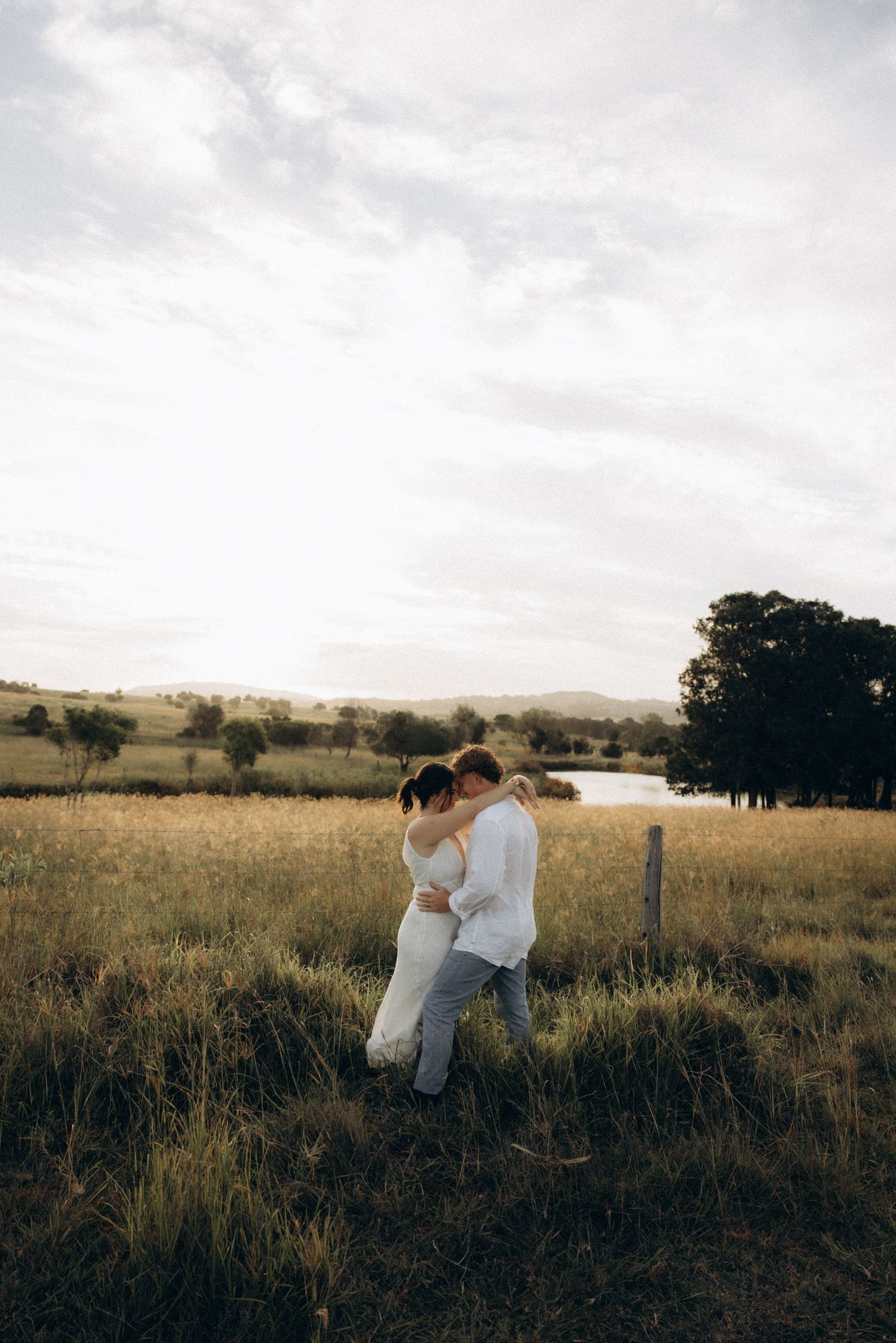 Romantic silhouettes against sunset sky in rural field setting.
