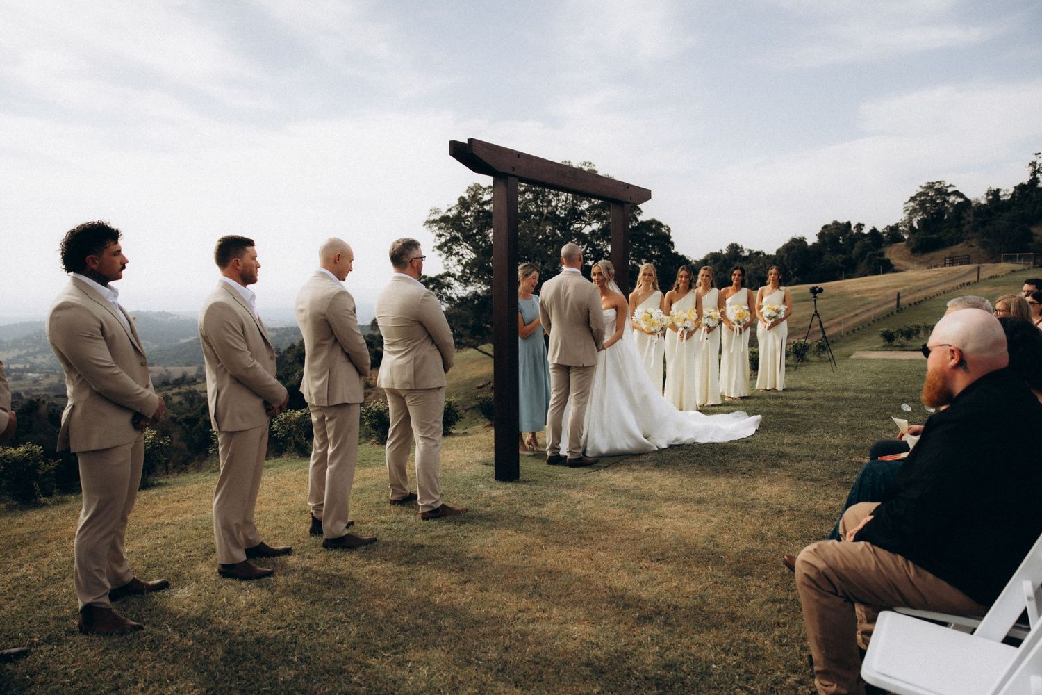 Panoramic view of wedding ceremony setup on a hilltop with guests seated under open sky.