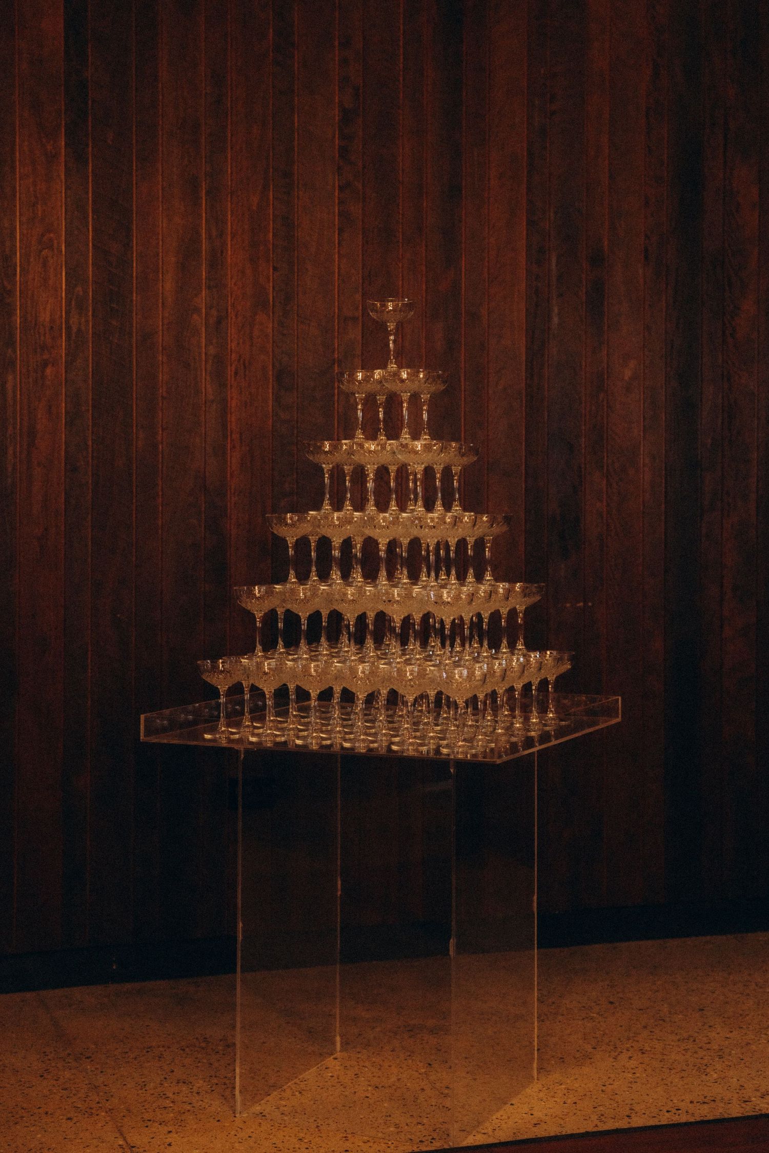 Elegant champagne glass tower display against dark wooden backdrop.