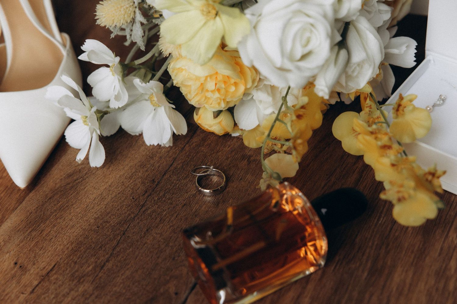 Yellow and white floral arrangements with roses displayed on a dark wooden surface.