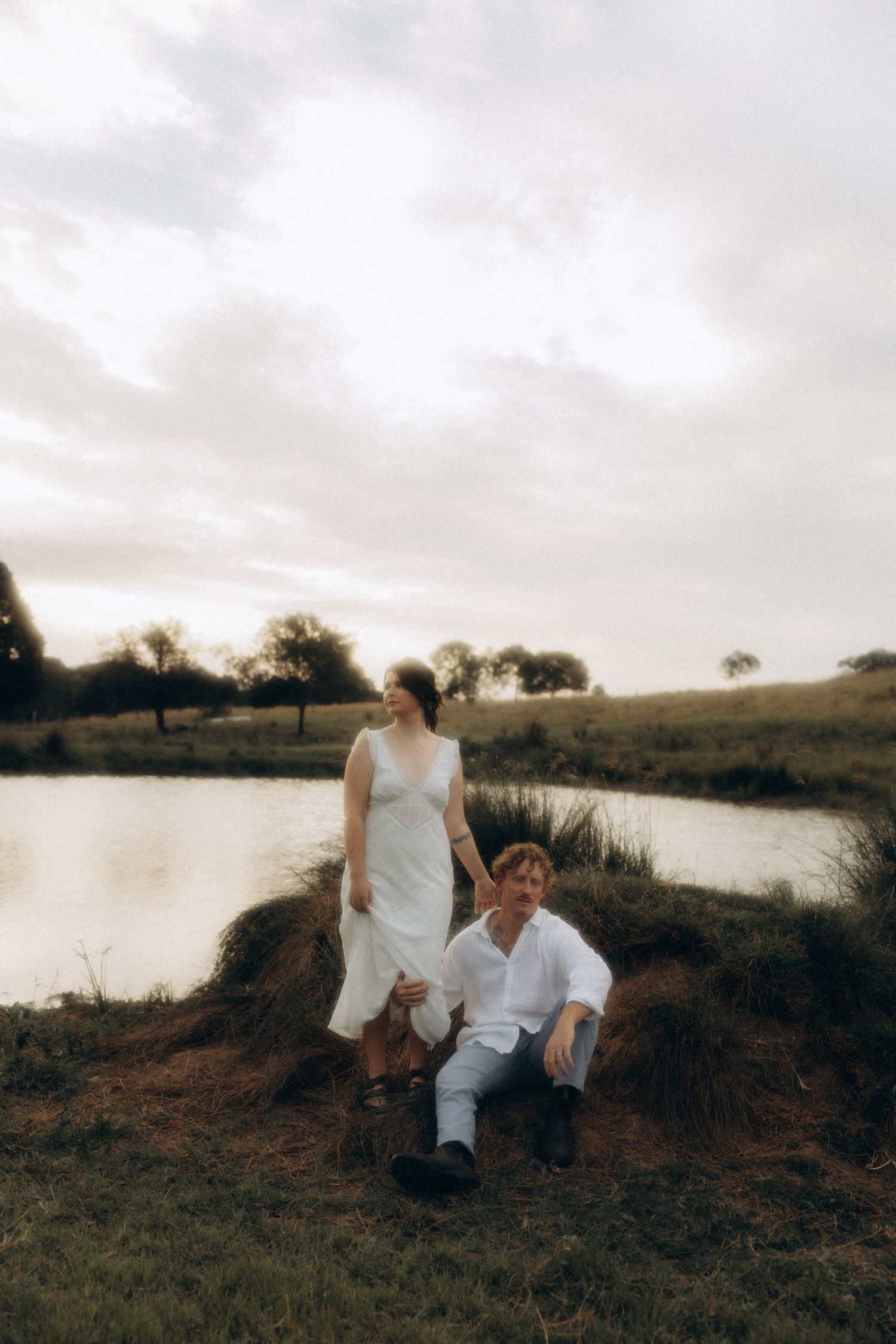 Couple relaxing by a peaceful lake during sunset.