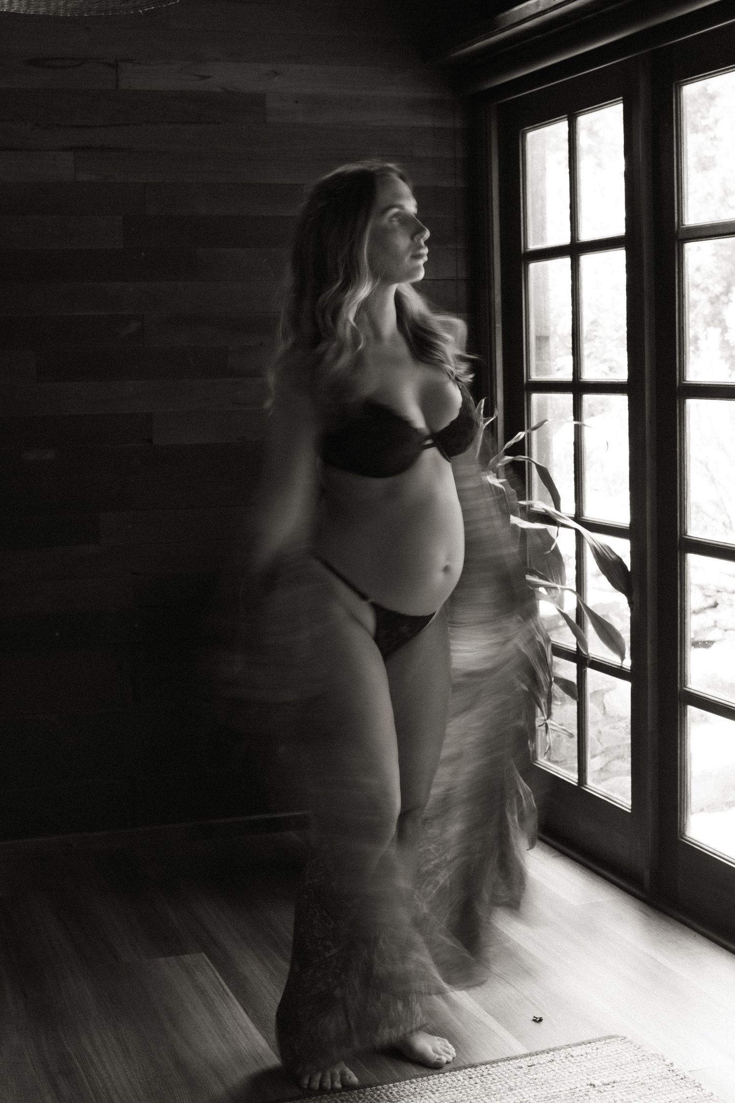 Artistic black and white photo of movement near a window with dramatic lighting.